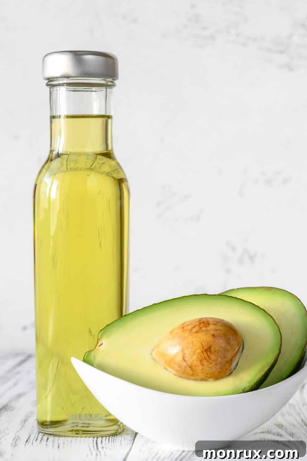 jar of avocado oil with a sliced fresh avocado next to it