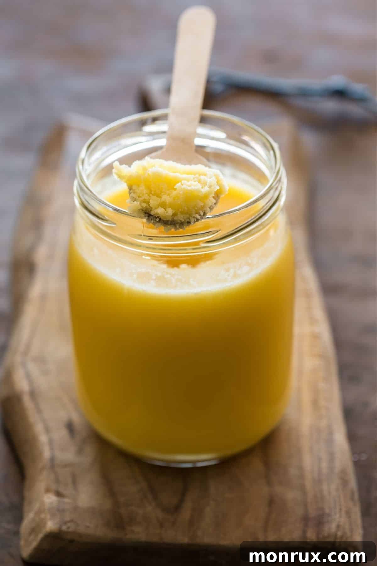 jar of ghee on a wood countertop with a wooden spoon 