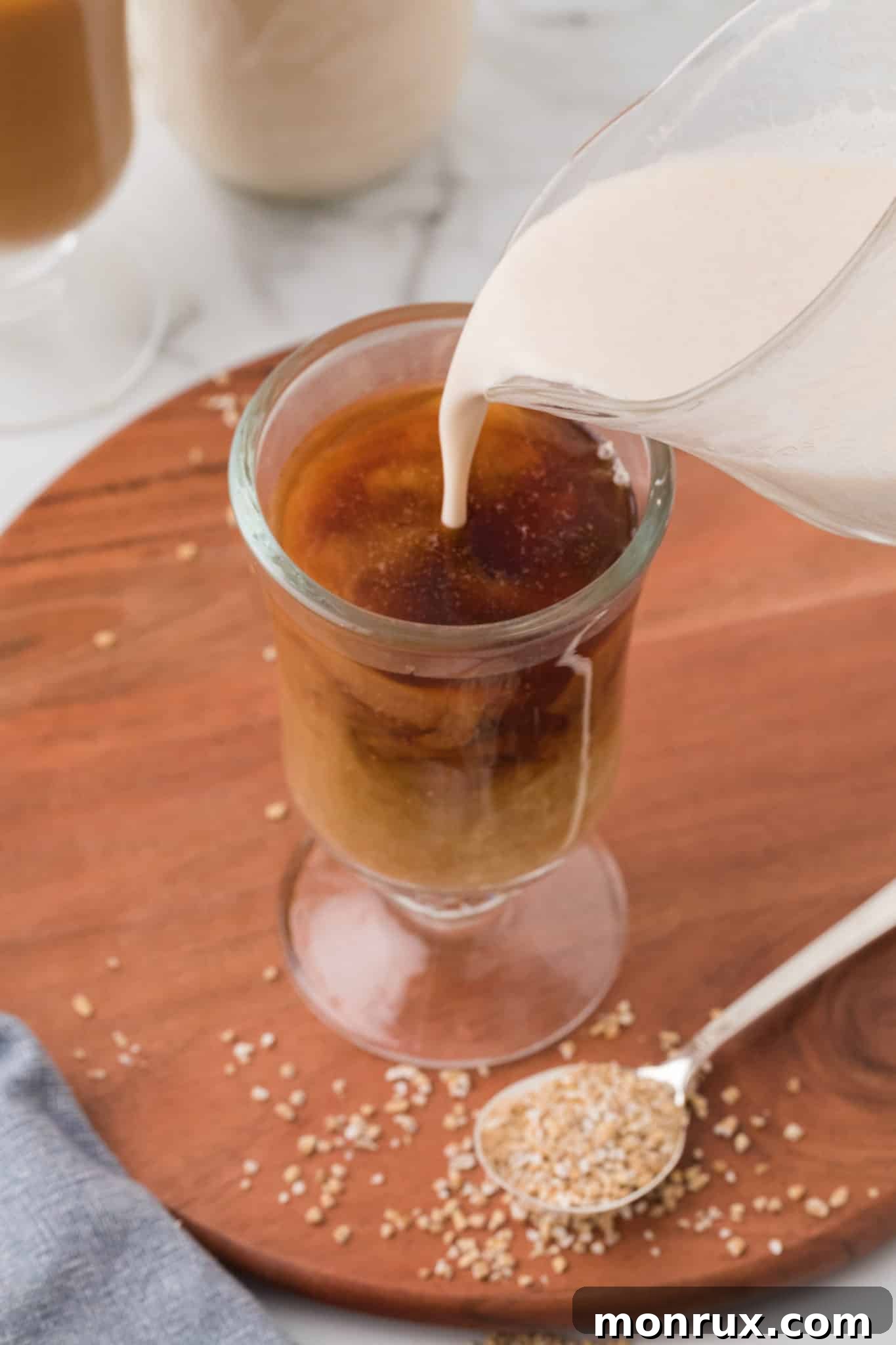 Pouring homemade oat milk creamer into a cup of coffee.