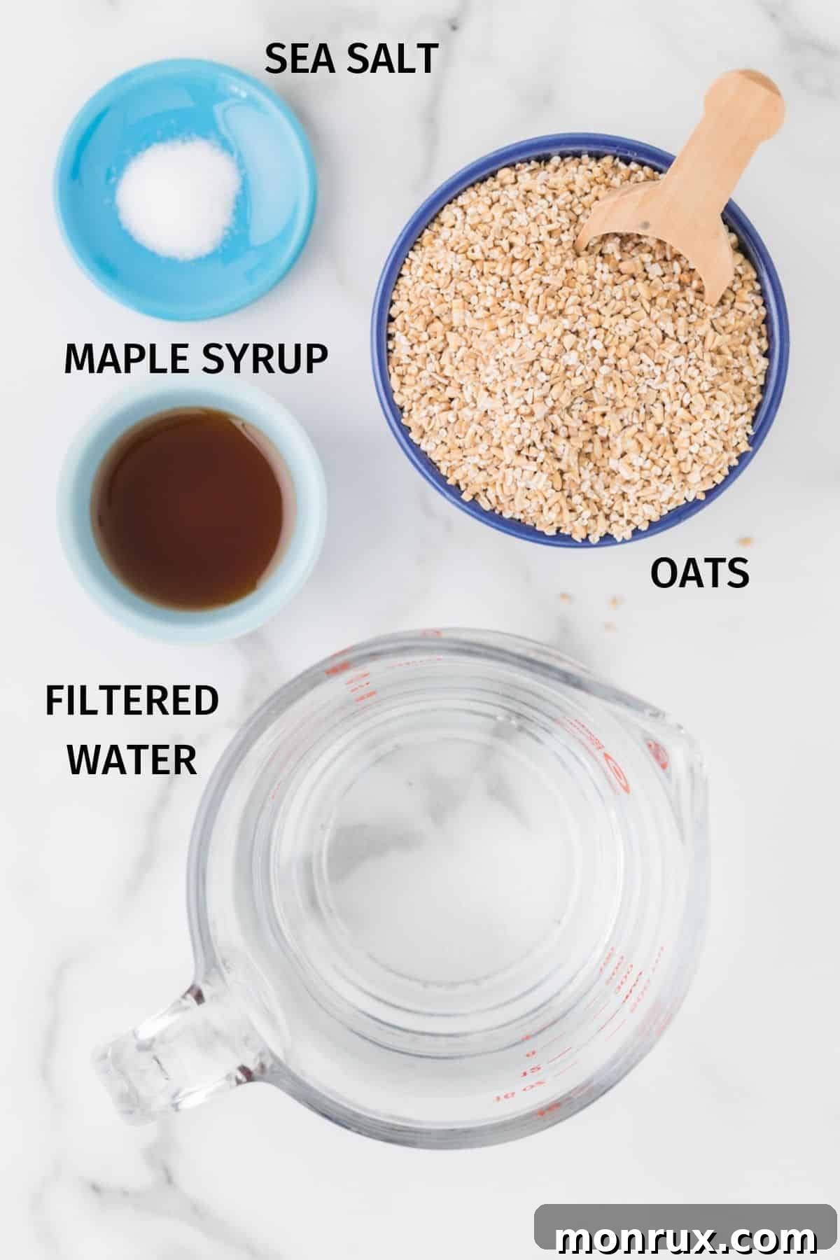 A flat lay photograph showcasing the simple ingredients needed to make oat milk creamer: steel cut oats, filtered water, maple syrup, and sea salt.