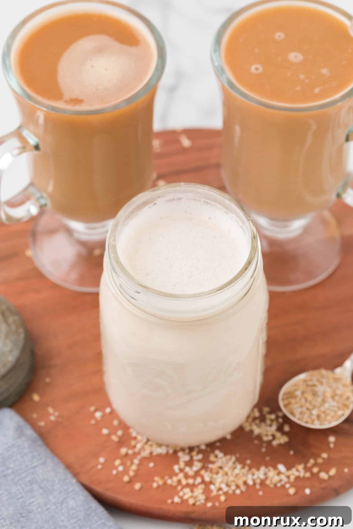 Two cups of coffee, one with oat milk creamer poured in, set on a wooden table.