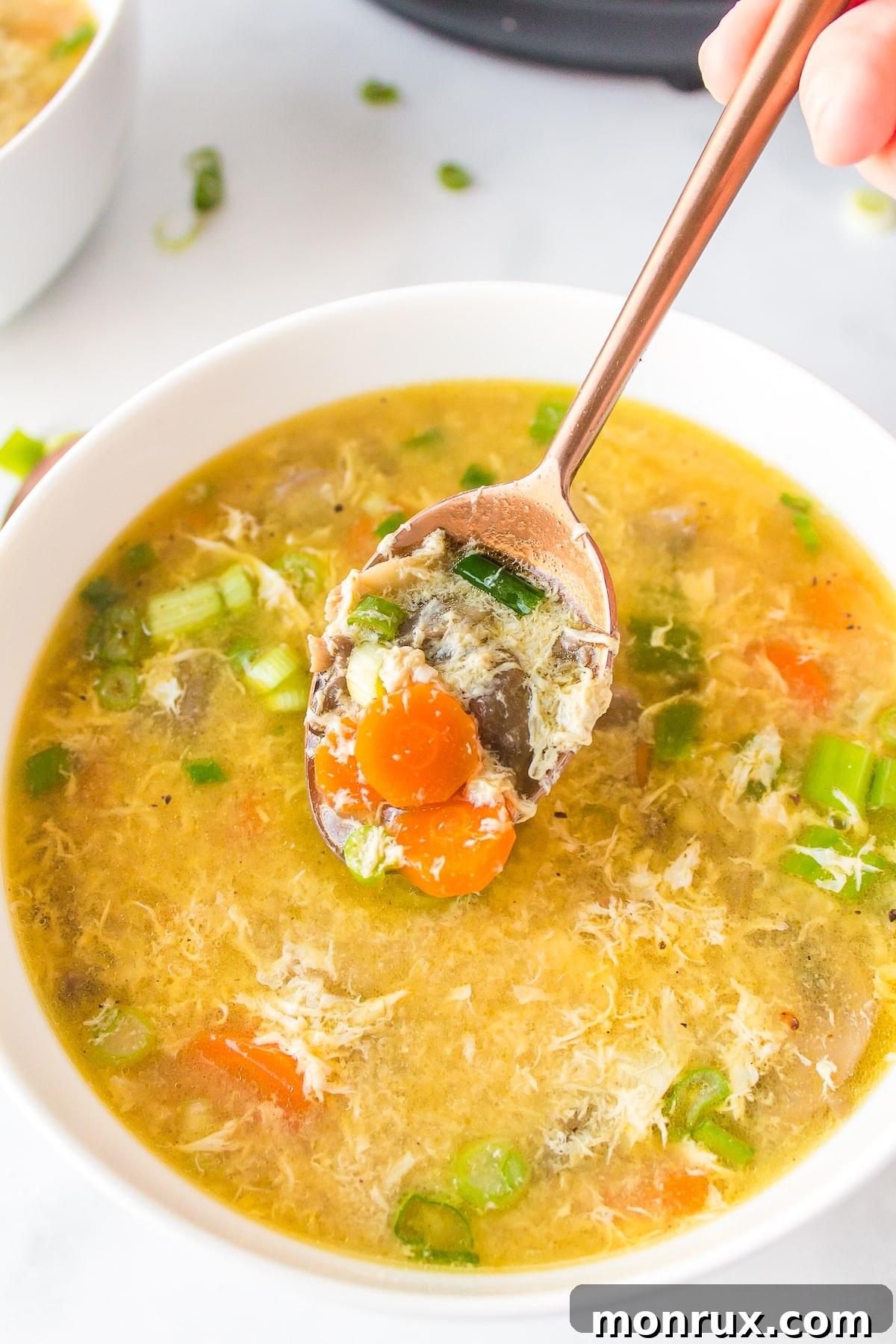 A beautifully presented bowl of Instant Pot egg drop soup with a spoon, highlighting its comforting and healthy appeal.