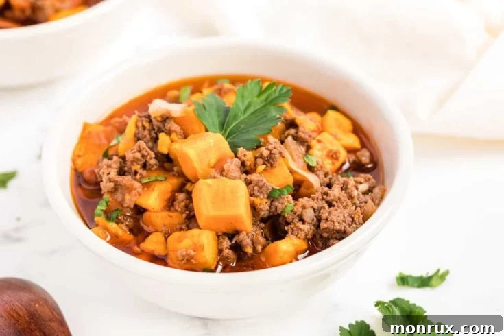 A bowl of rich Instant Pot Beef Chili with Sweet Potatoes, garnished with fresh herbs.