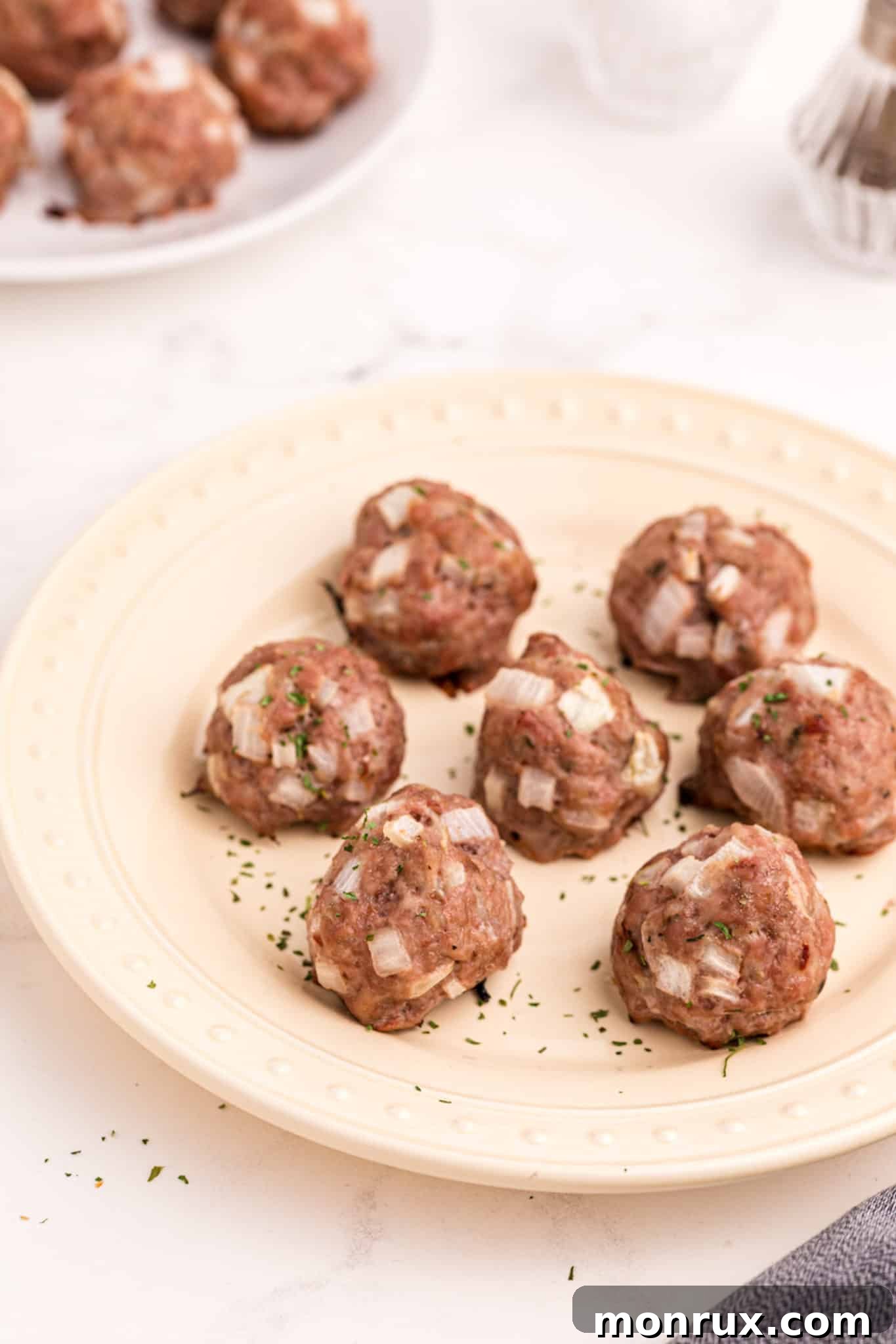 plate of cooked pork meatballs, garnished with fresh herbs