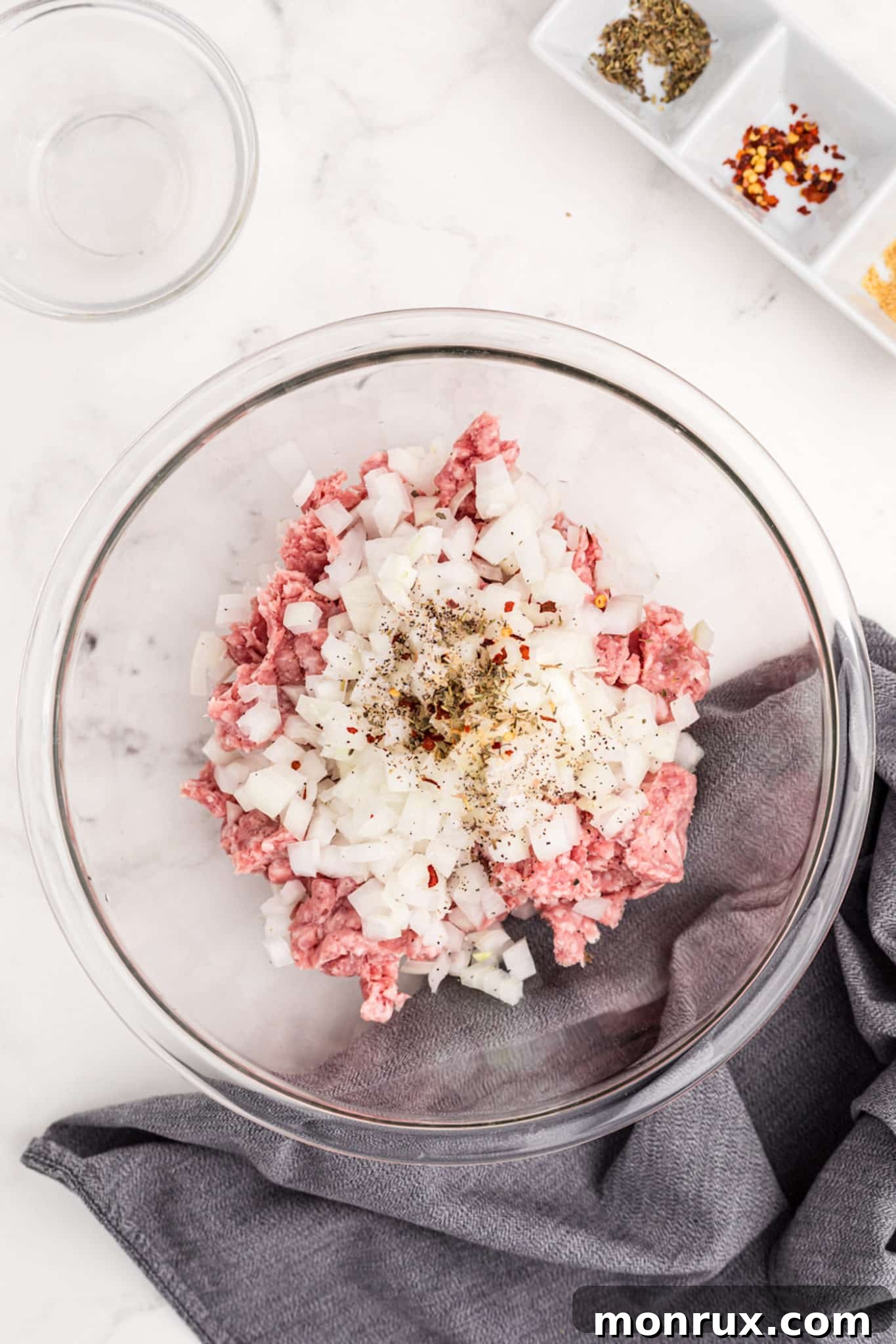 bowl with ground pork, chopped onion, and spices