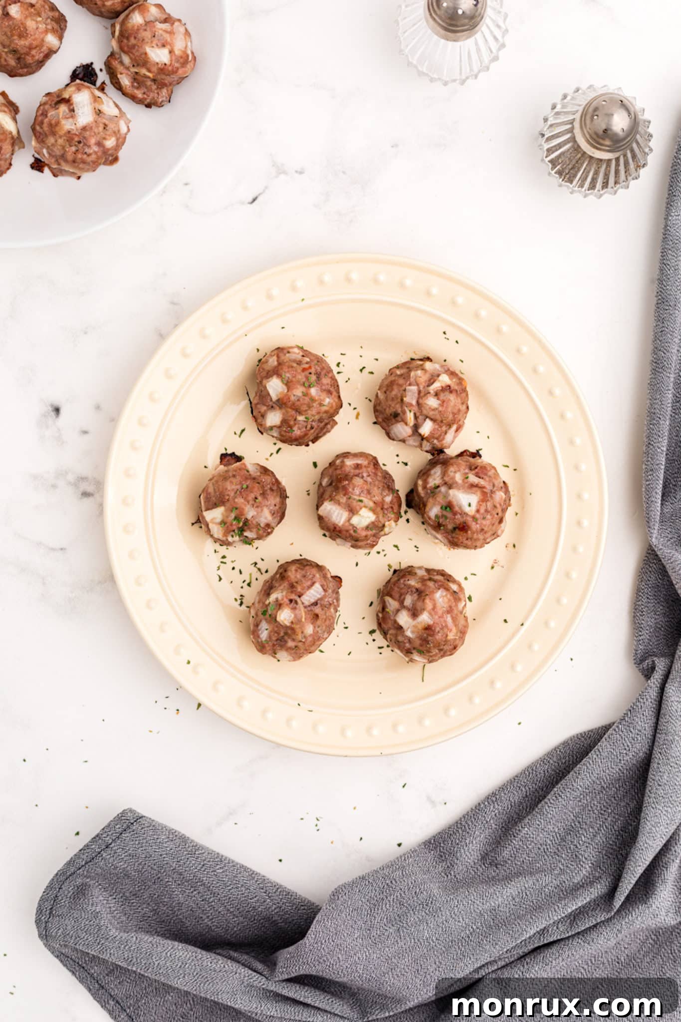 two plates with baked pork meatballs and side dishes