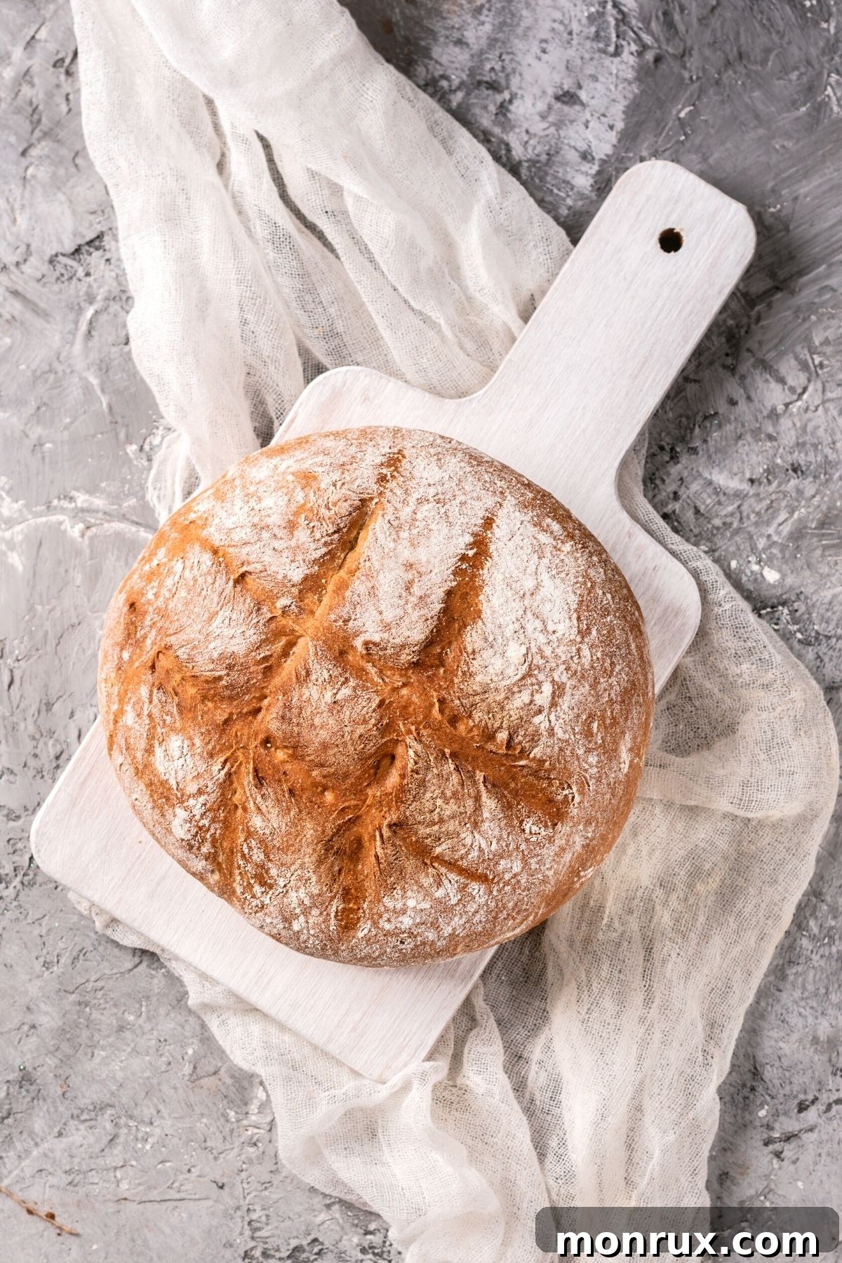 A freshly baked loaf of sourdough bread on a cutting board, with a rustic, crackled crust.