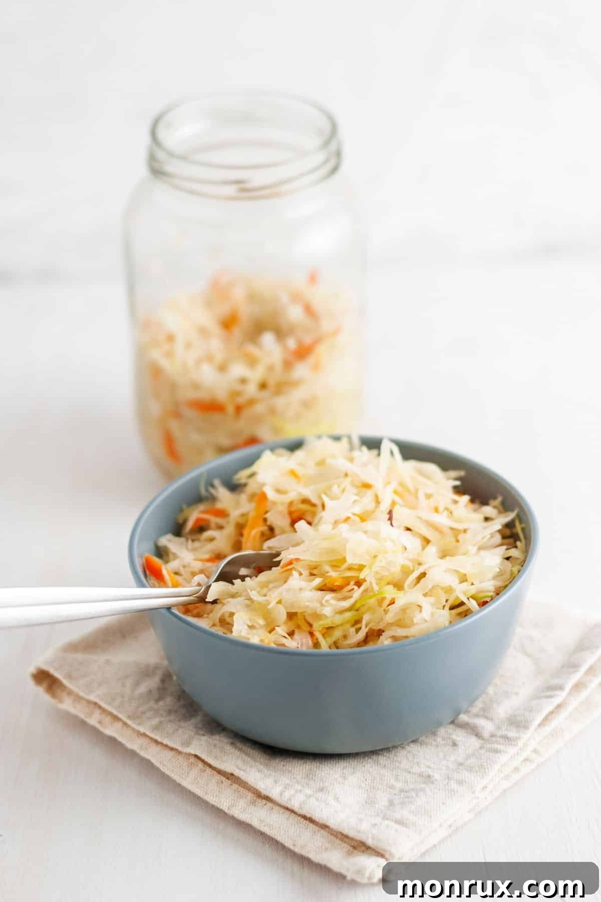 A rustic jar and bowl filled with homemade sauerkraut, glistening with brine and ready to be enjoyed.