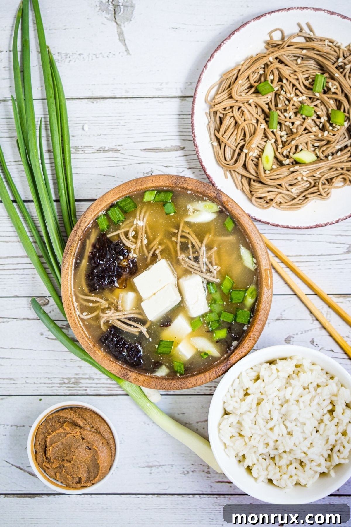 A selection of miso paste varieties and a steaming bowl of miso soup, highlighting its diverse culinary uses.