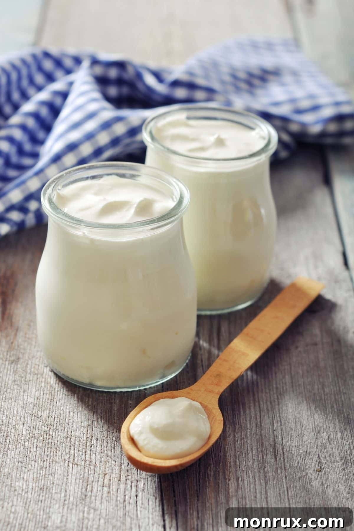 Individual jars of creamy yogurt, some plain and some topped with fruit, ready for a healthy meal.