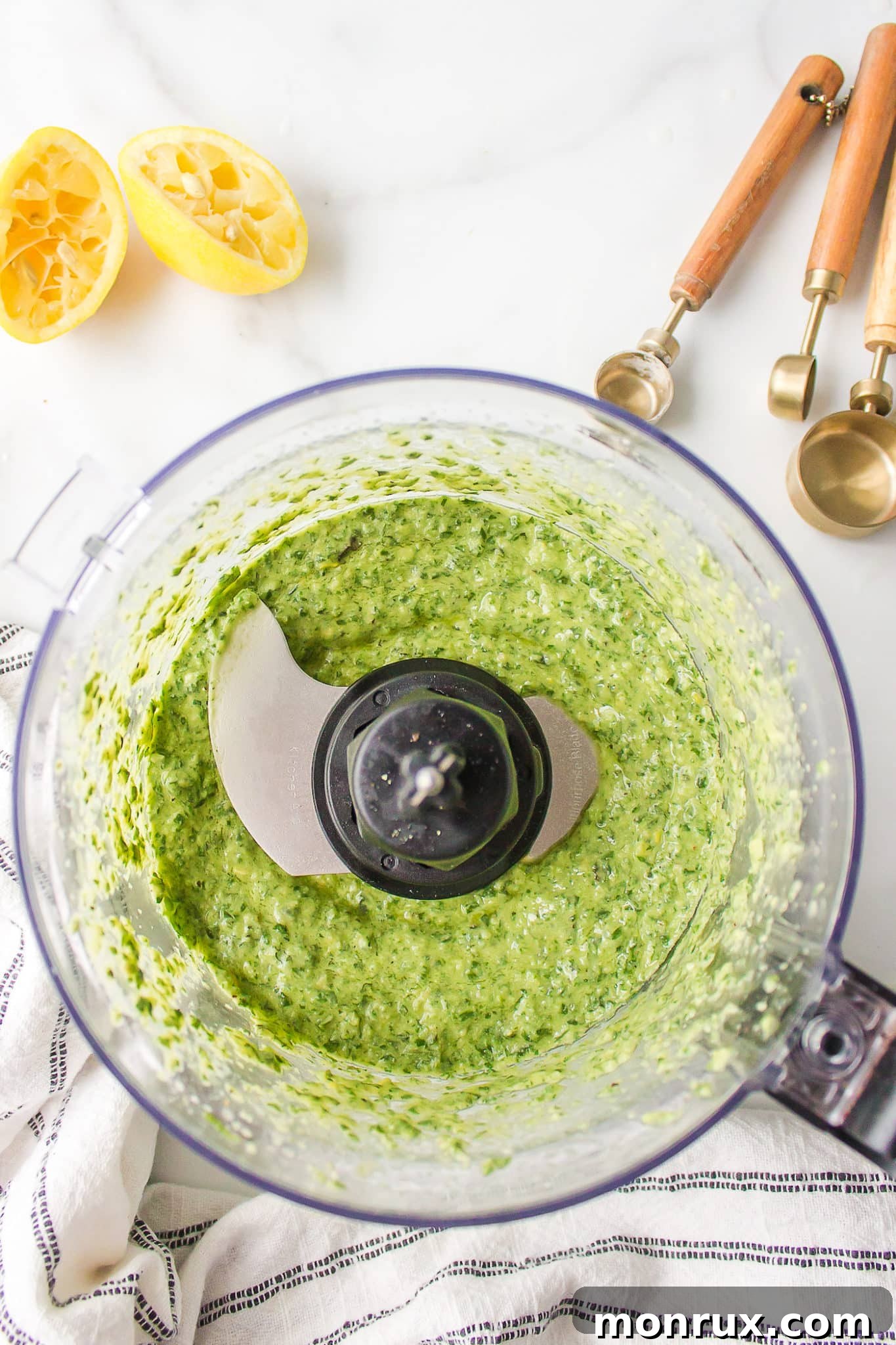 Lush green dairy-free pesto sauce blended smooth in the bowl of a food processor.