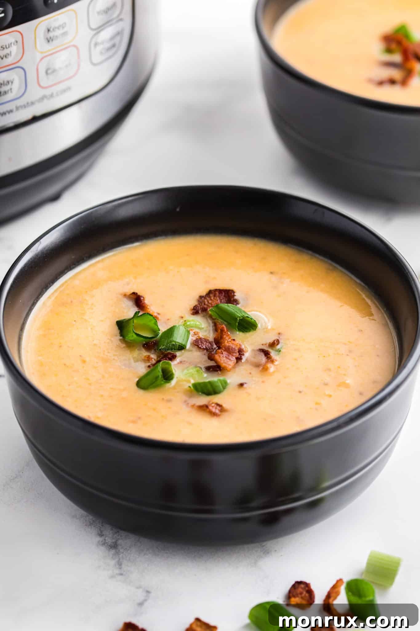 A bowl of dairy-free potato soup topped with bacon crumbles and fresh herbs.