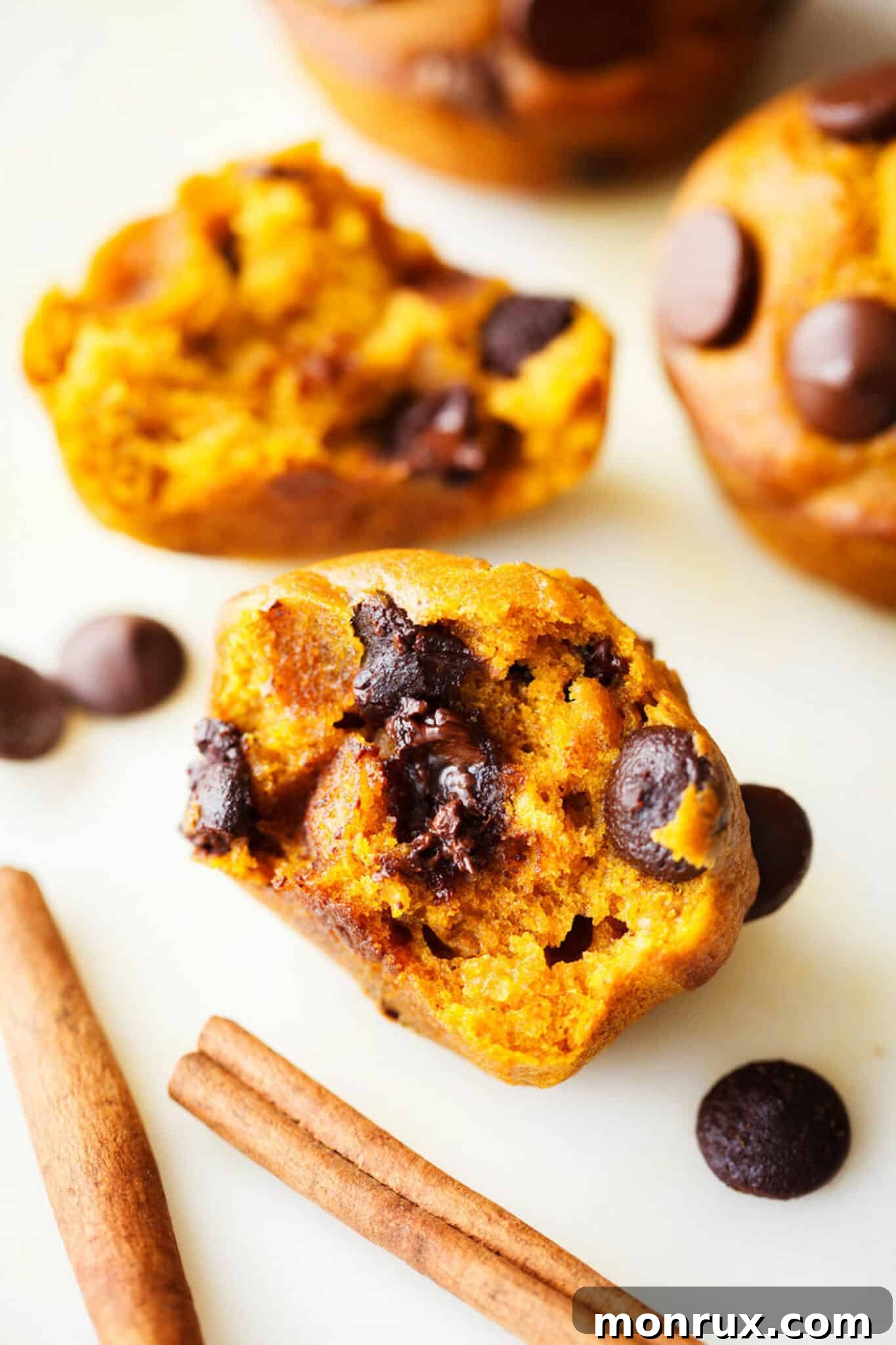 A perfectly baked gluten-free pumpkin chocolate chip muffin, sliced in half to show its moist, tender interior and abundant chocolate chips.