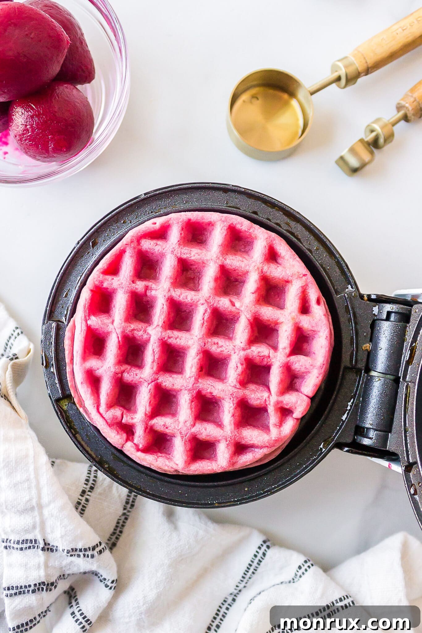 A freshly cooked, perfectly pink waffle nestled in the grids of a waffle iron, showcasing its crisp edges and inviting color.