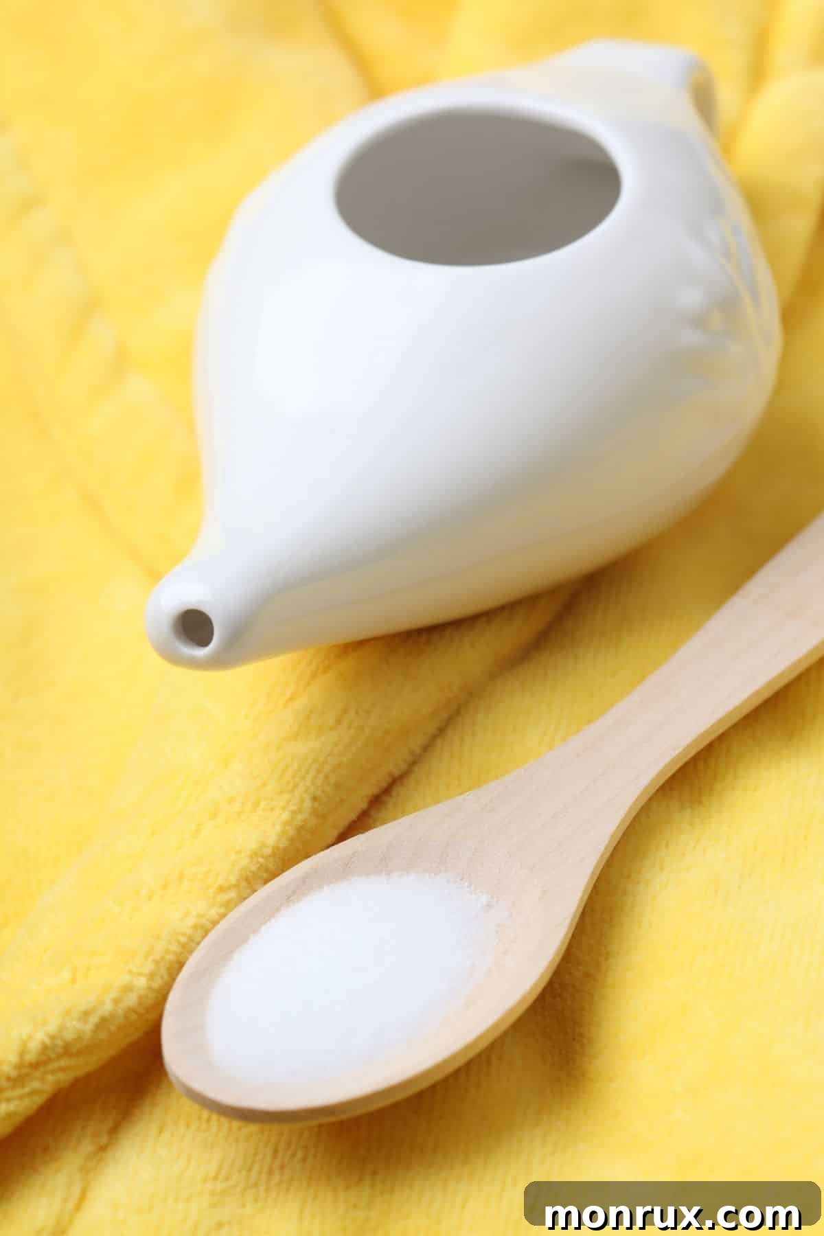 Neti pot on a table with a spoonful of salt, ready for nasal irrigation.