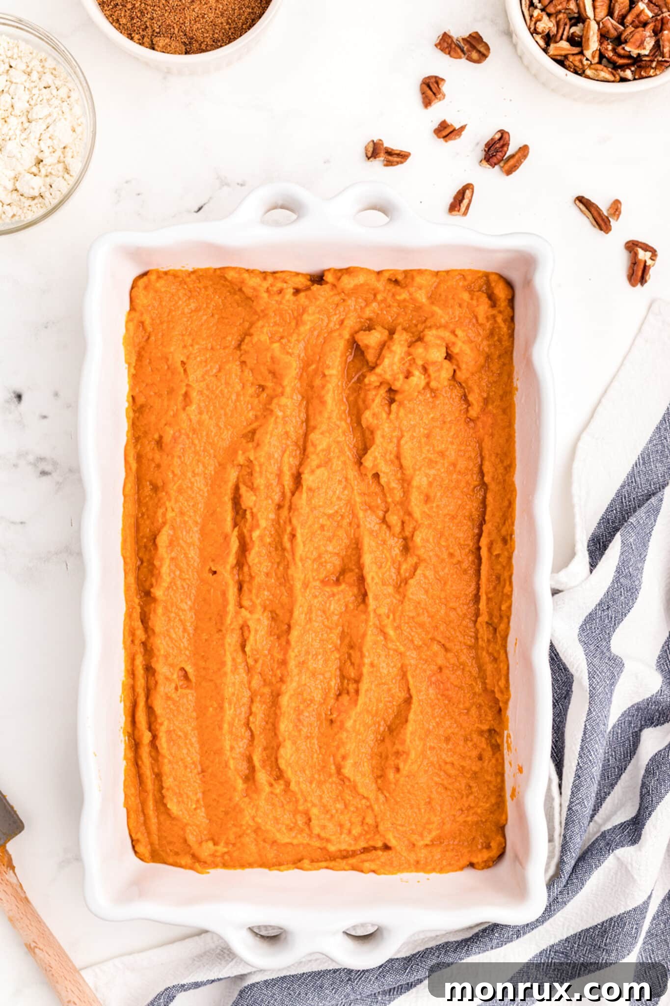 Sweet potato casserole filling neatly spread into a white rectangular baking dish, ready for its topping.