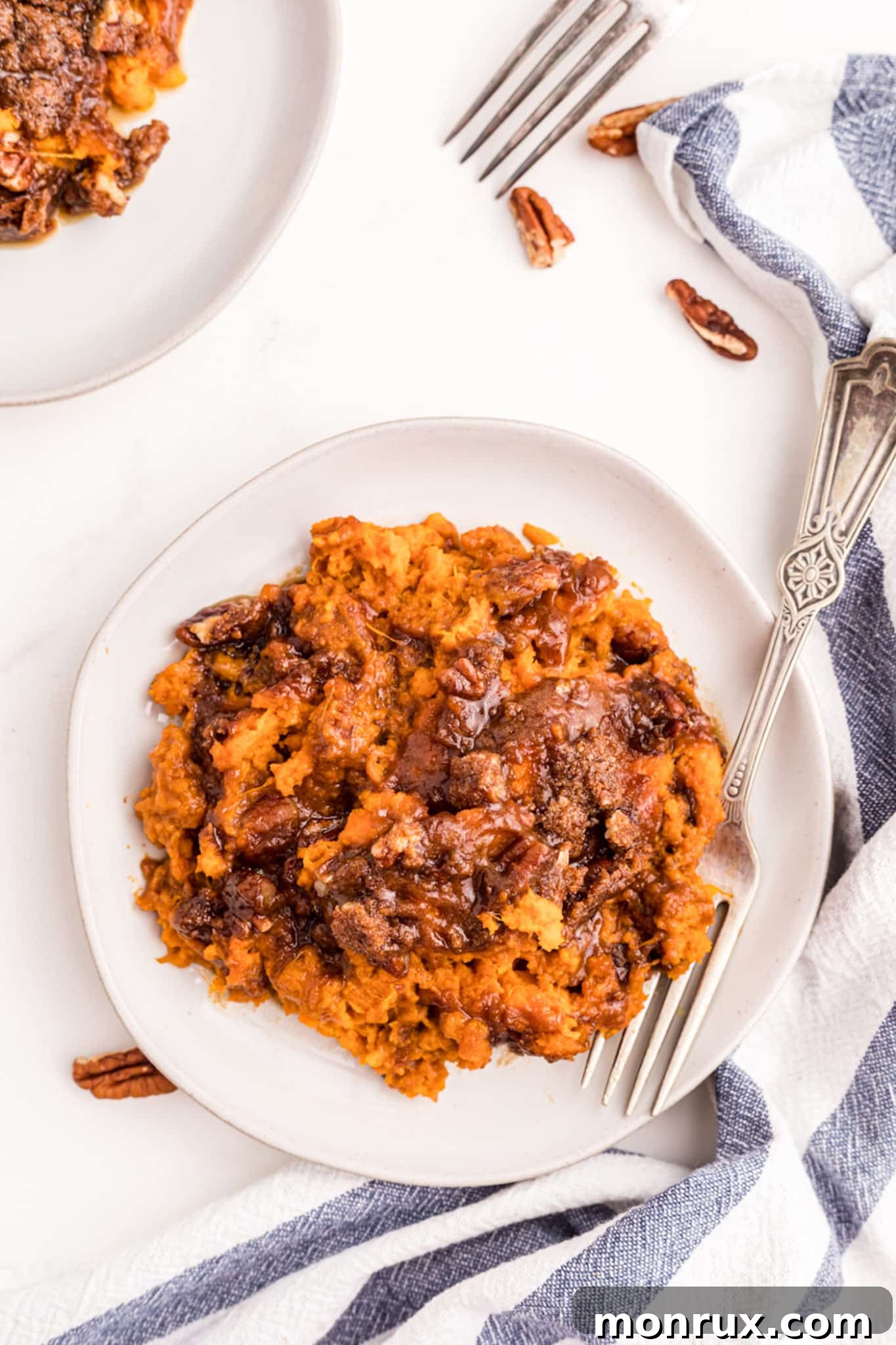 A serving of gluten-free sweet potato casserole with its crunchy pecan crumb topping, placed on a white plate, ready to be enjoyed.