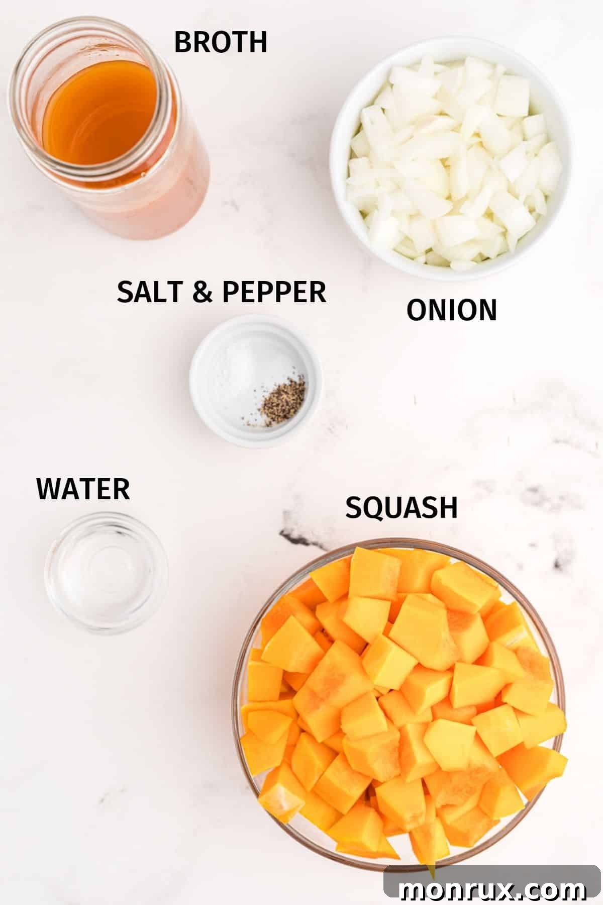 Fresh butternut squash, an onion, and vegetable broth carton on a rustic wooden surface.