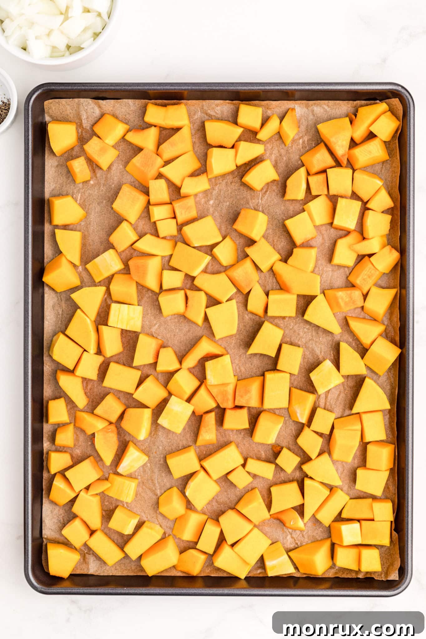 Cubed butternut squash spread on a baking sheet, ready for roasting.
