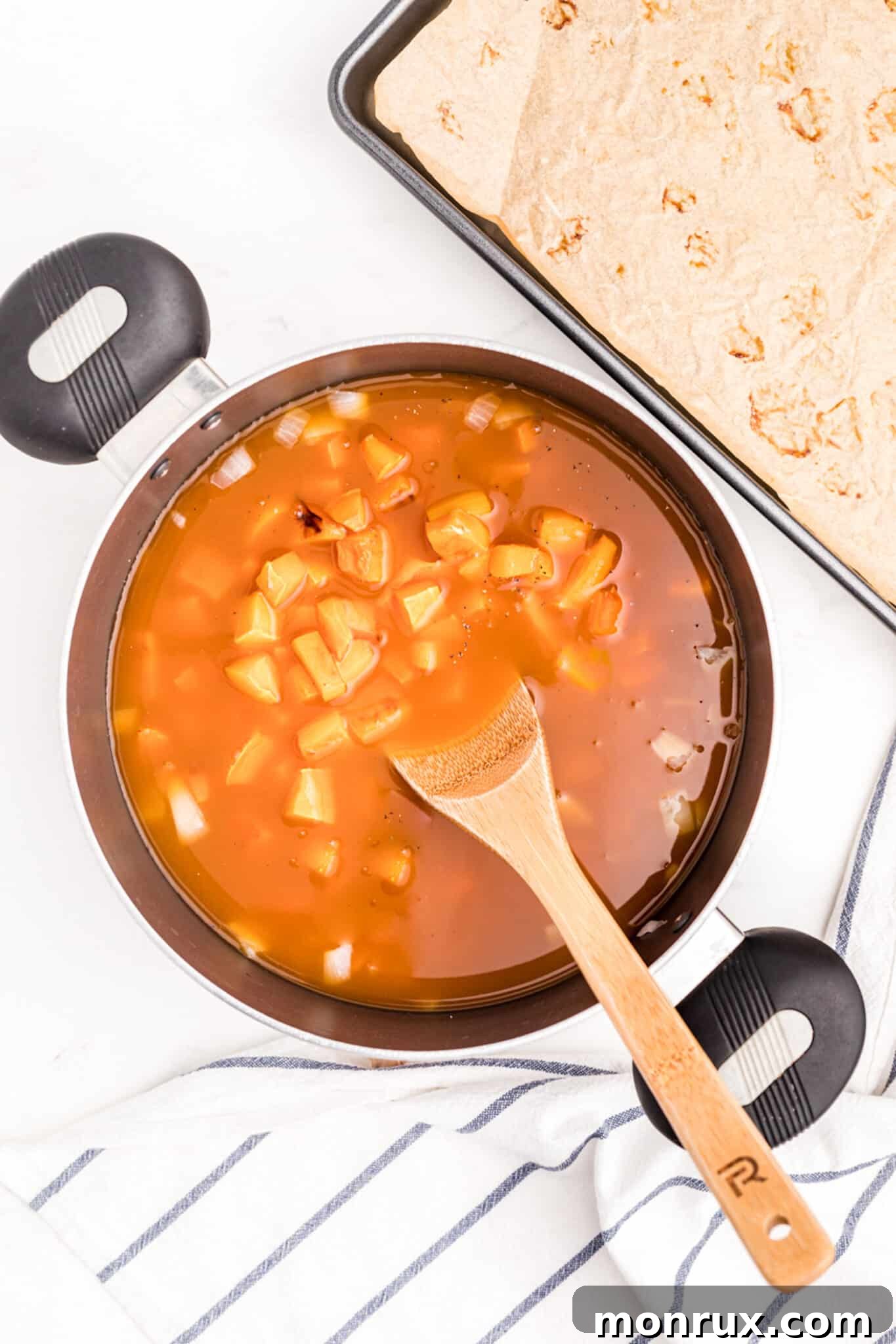 Vegetables simmering in broth in a stockpot on the stovetop.
