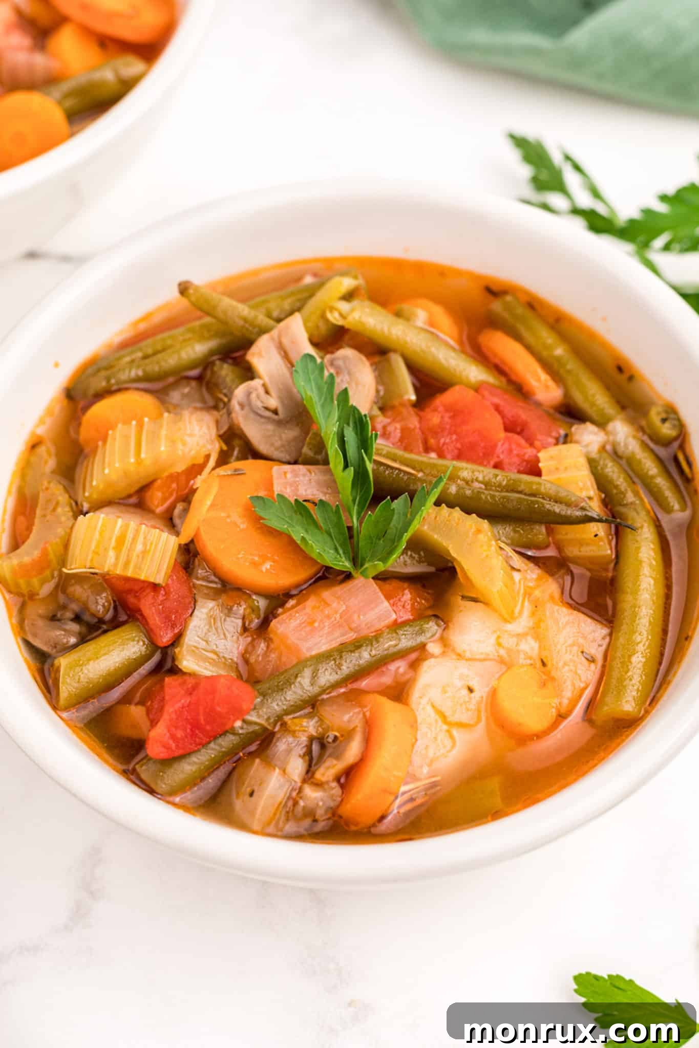 a bowl of vegetable stew with potatoes topped with parsley garnish.