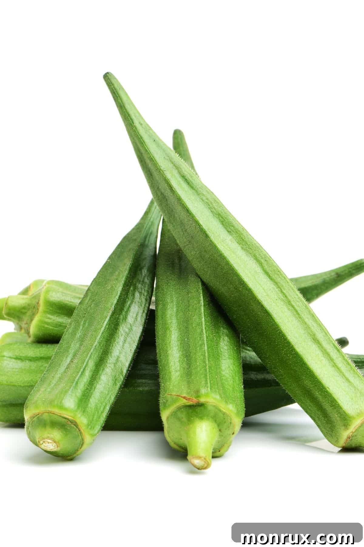 Several fresh green okra pods arranged on a clean white background, showcasing their unique ribbed texture.