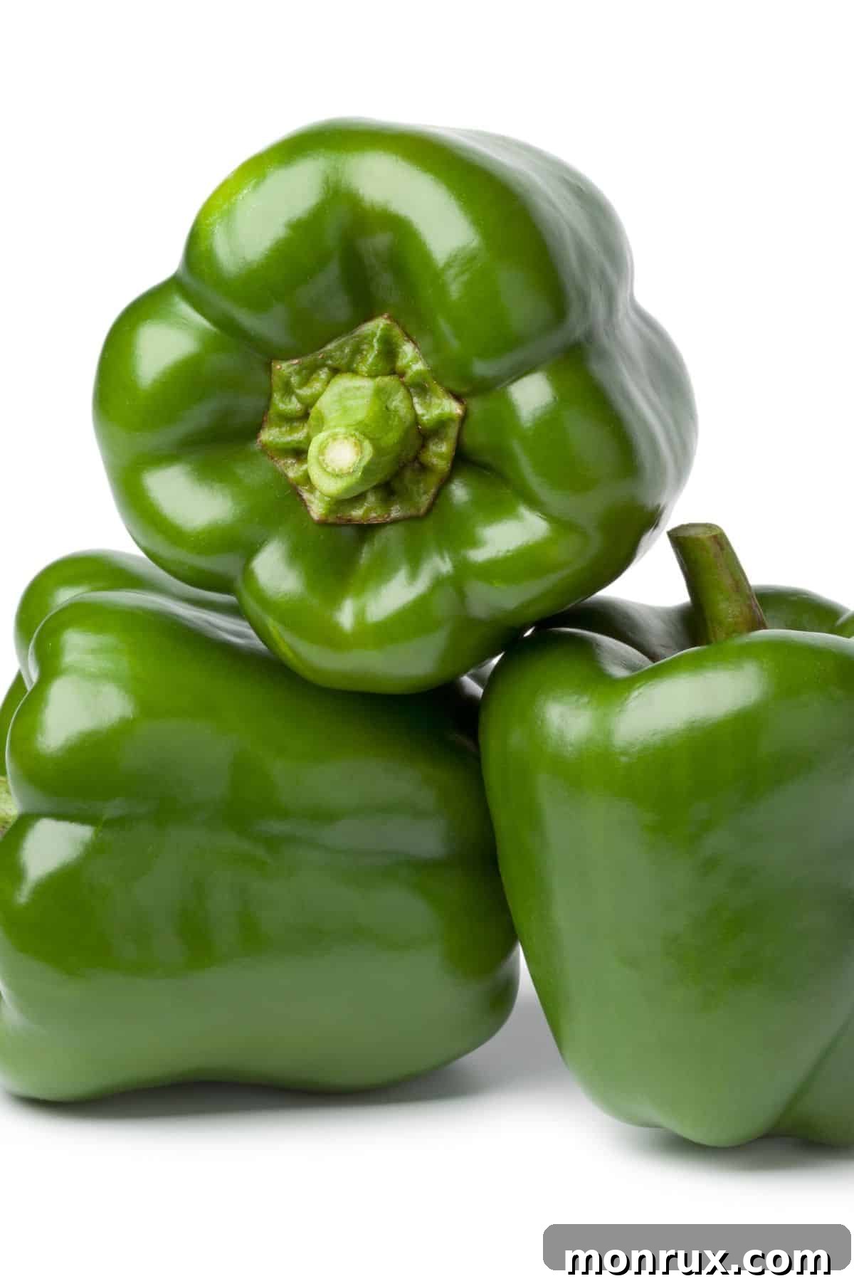 A vibrant pile of fresh green bell peppers on a wooden table, emphasizing their glossy skin and round shape.