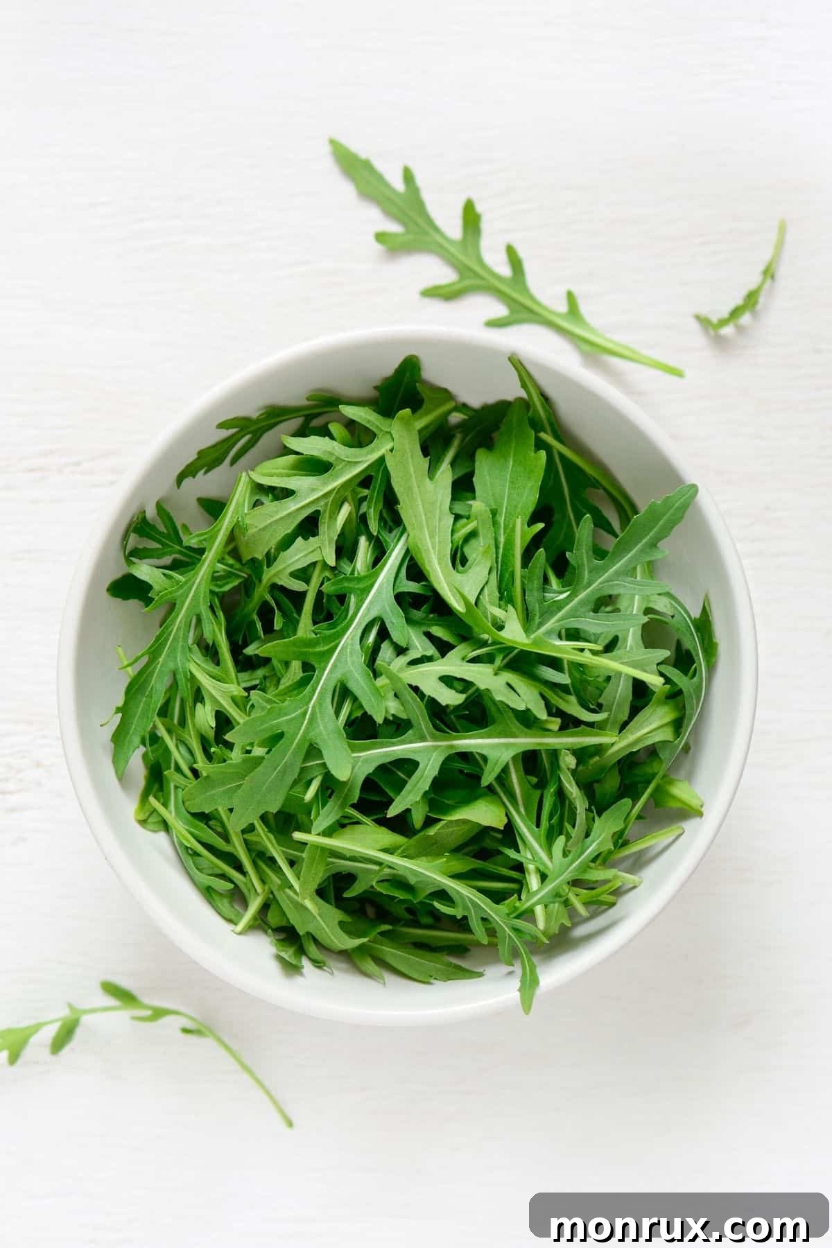A bowl filled with fresh, vibrant arugula leaves, showcasing their delicate texture and deep green color.