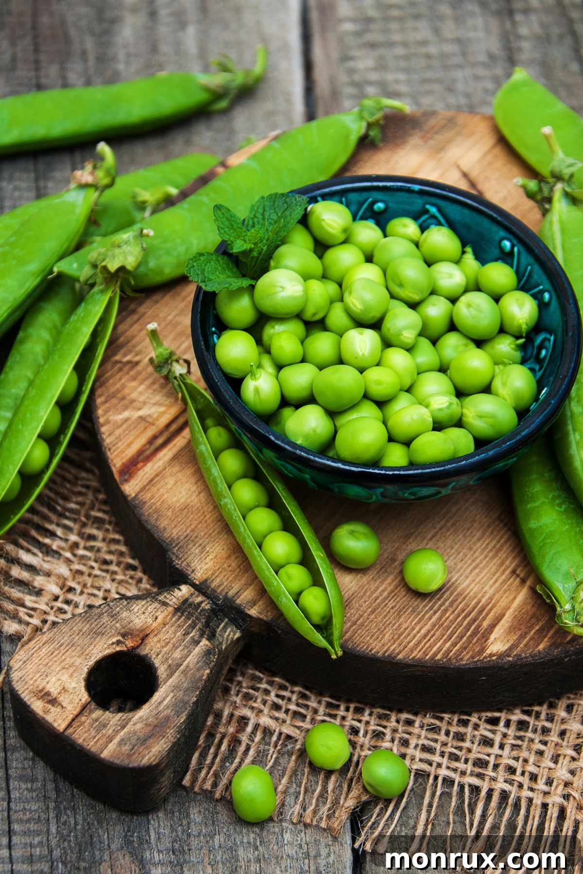 A cluster of fresh green peas still in their pods, alongside shelled peas on a wooden table.