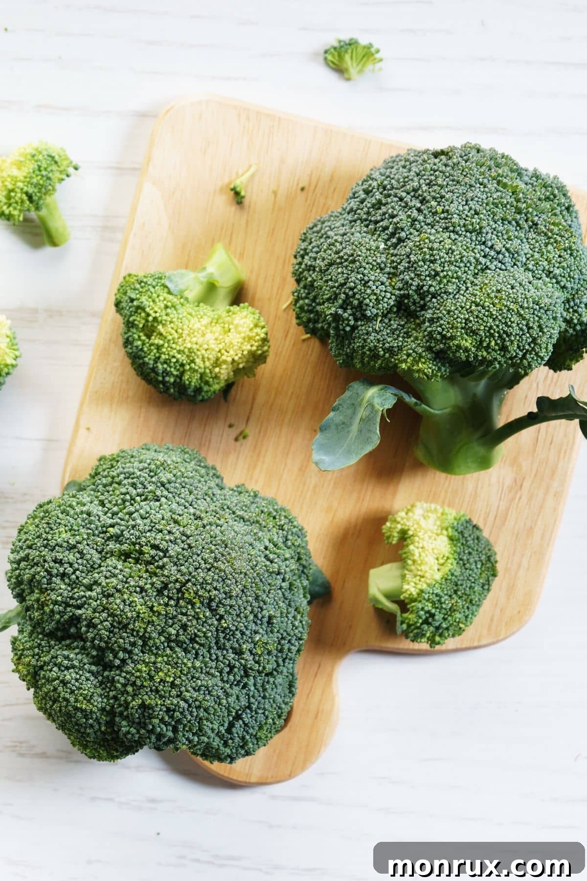 Fresh head of broccoli on a wooden cutting board, ready for preparation.