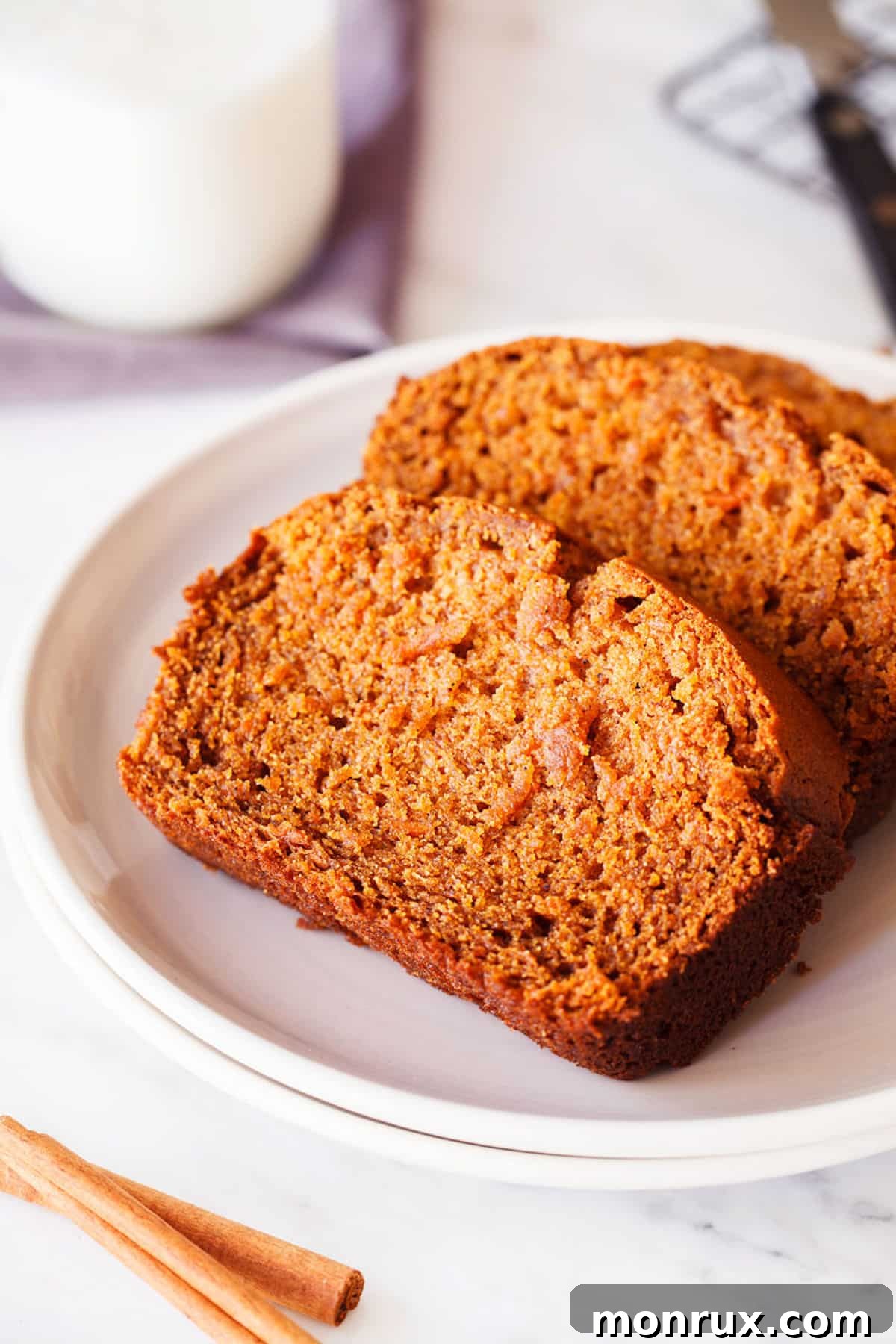 Two golden-brown slices of freshly baked gluten-free sweet potato bread, featuring a moist, tender crumb, arranged on a white plate with a subtle garnish.