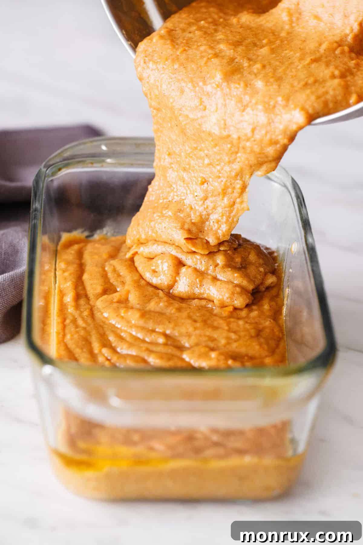 A large mixing bowl containing the thick, rich batter for sweet potato bread, showing the vibrant color and smooth consistency before baking.