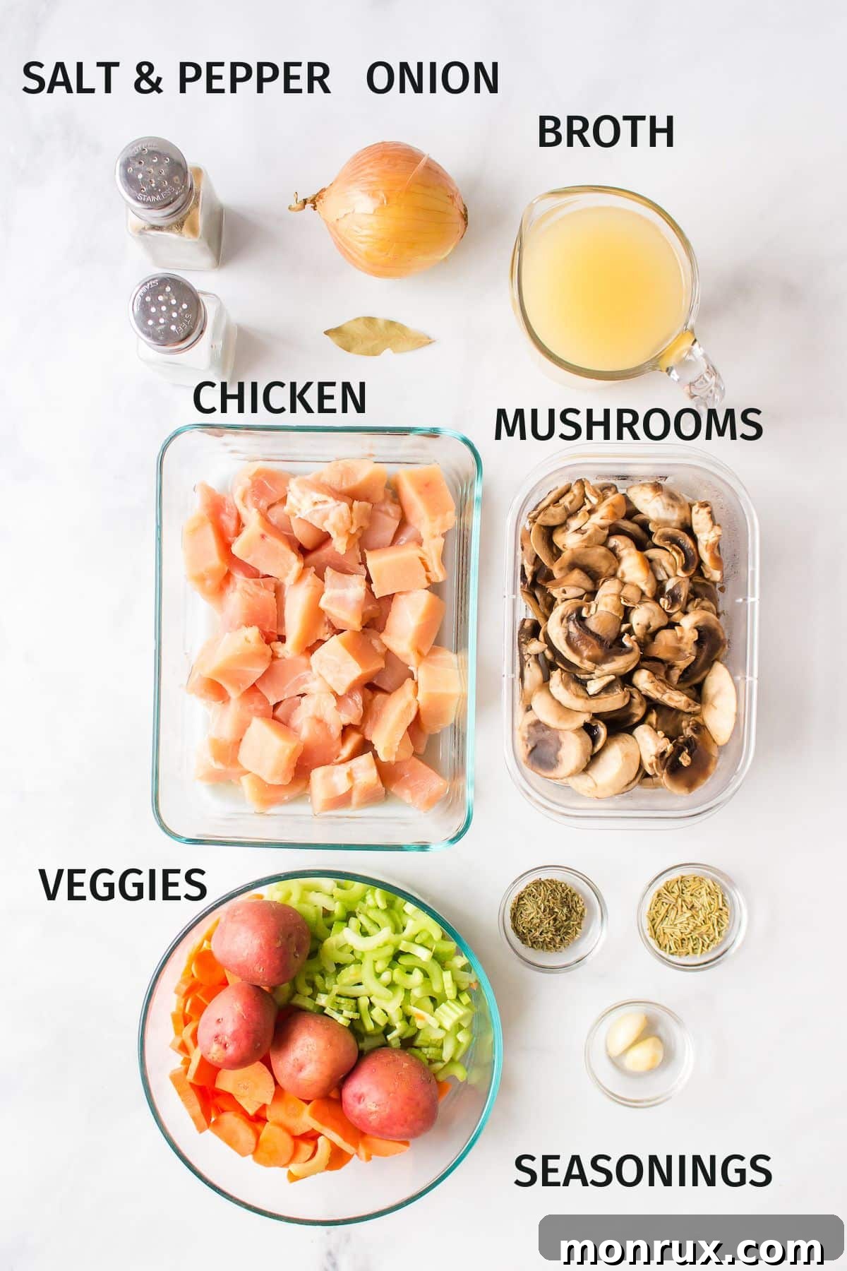 Assorted fresh ingredients for chicken and potato soup laid out on a wooden board.