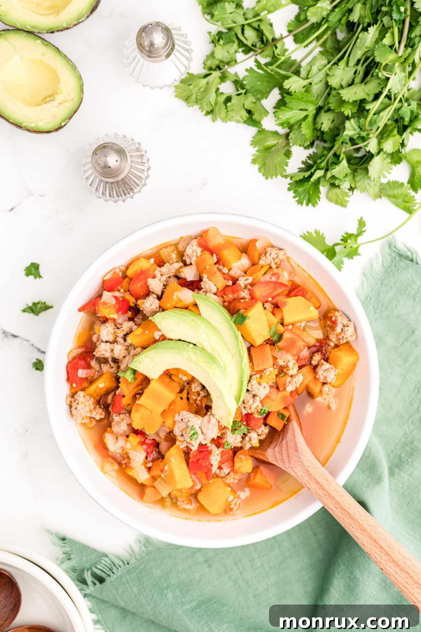 A vibrant bowl of hearty turkey chili without beans, garnished with fresh avocado and cilantro, ready to be enjoyed.