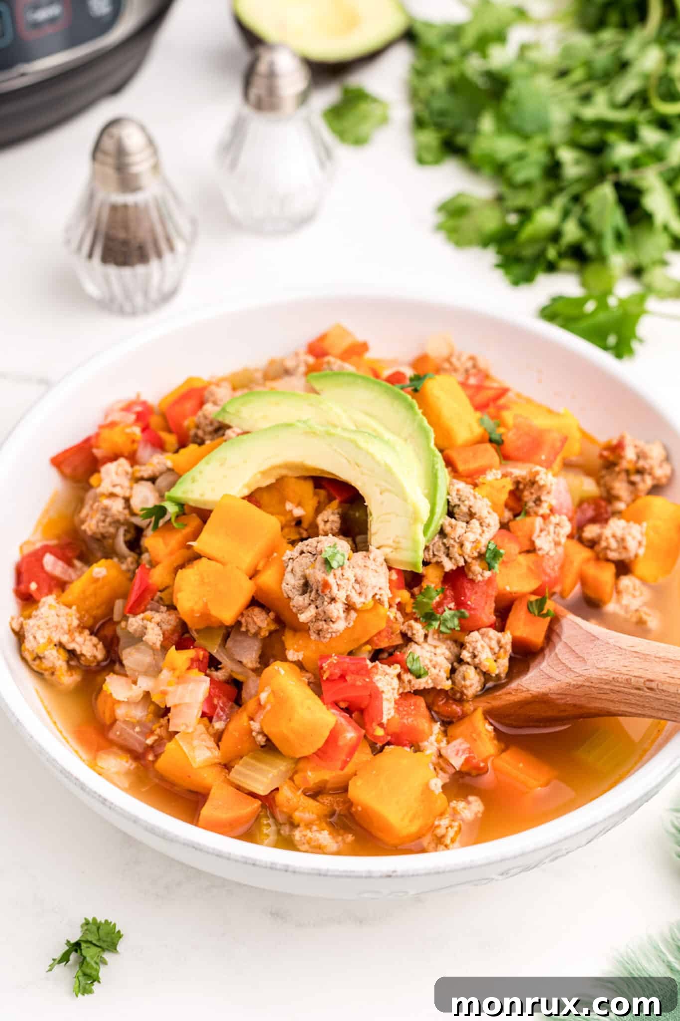 A delicious bowl of turkey and veggie chili, perfectly cooked and garnished, placed on a rustic table, invitingly ready to be eaten.