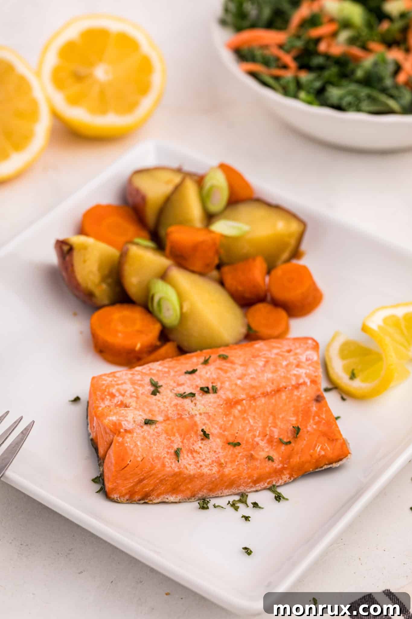 cooked salmon served with potatoes and carrots, garnished with fresh herbs
