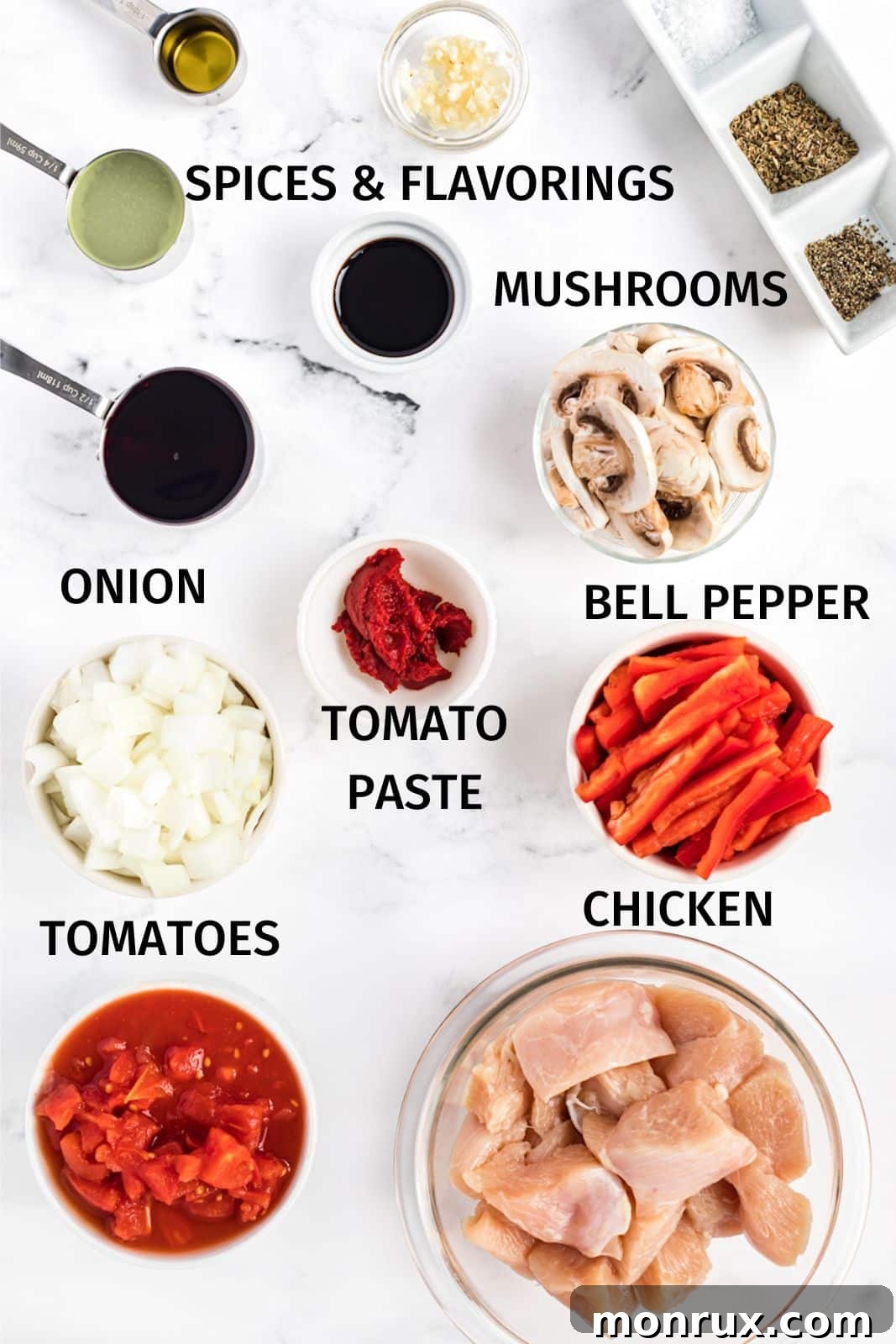 Ingredients laid out for Keto Chicken Cacciatore, including chicken pieces, bell peppers, mushrooms, canned tomatoes, garlic, and herbs.