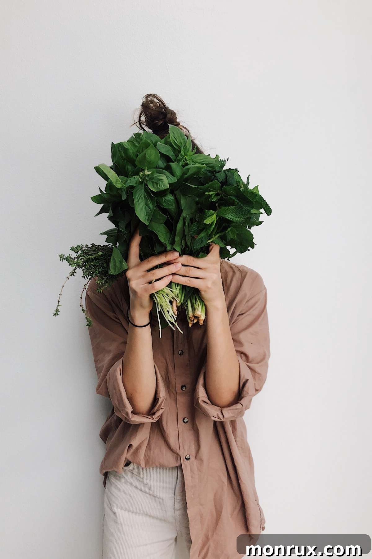 A woman peeking from behind a bounty of fresh green vegetables, emphasizing the abundance and joy of plant-based eating.