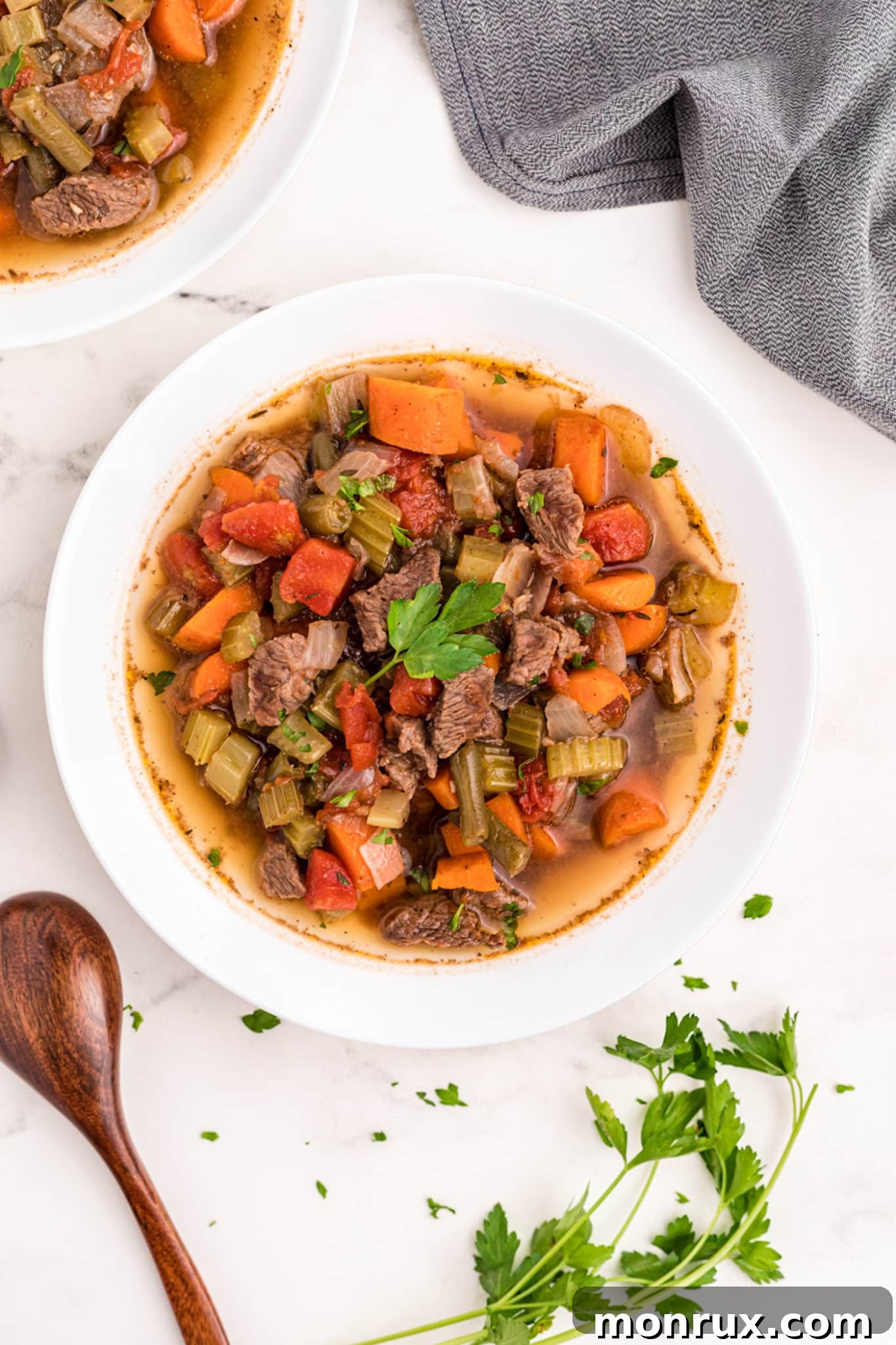 A steaming bowl of Instant Pot Vegetable Beef Soup, brimming with tender beef, carrots, celery, and green beans, served on a rustic wooden surface, ready to be enjoyed.