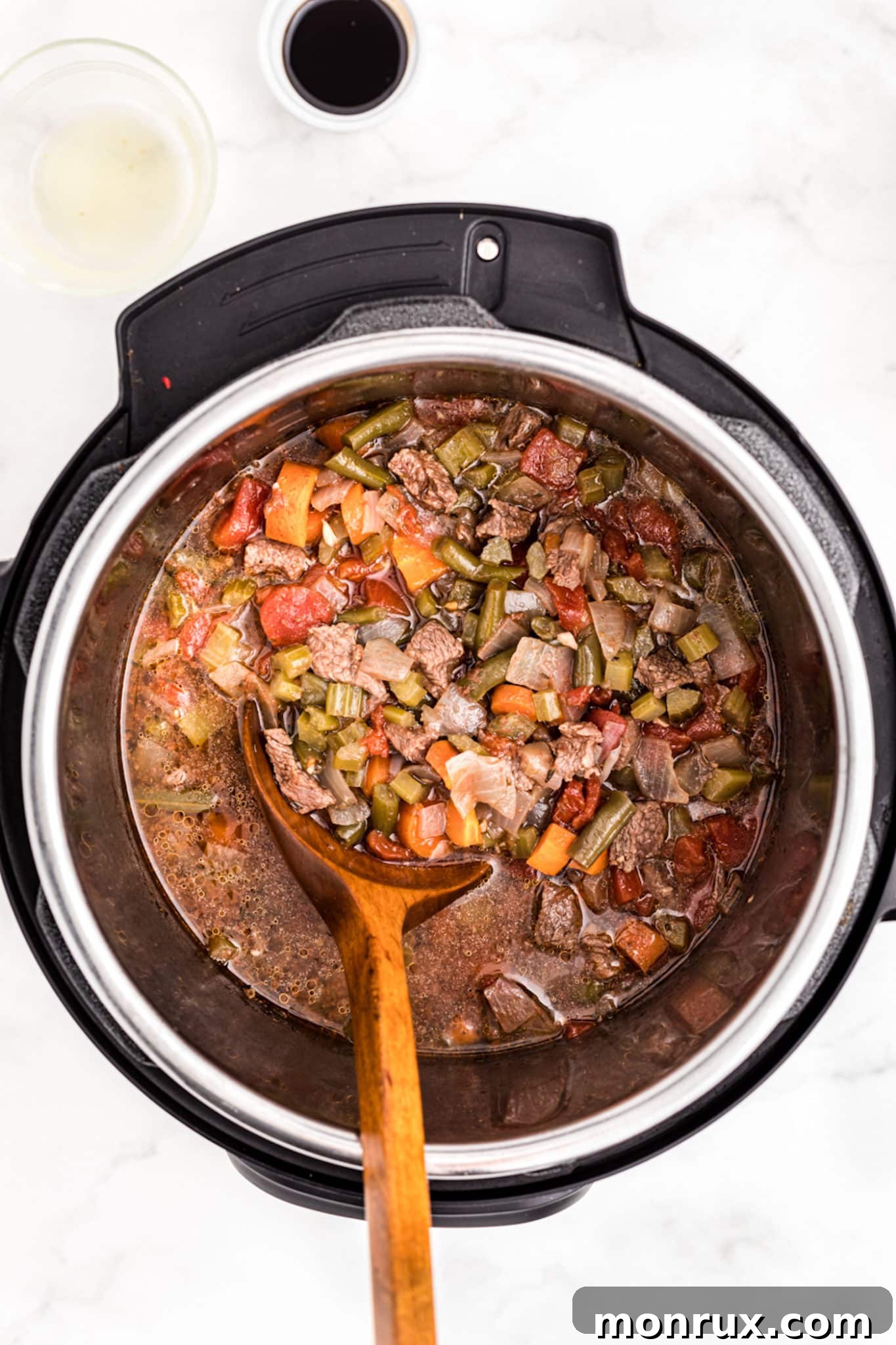 The finished Instant Pot Vegetable Beef Soup, still in the Instant Pot, with a serving spoon nestled within the rich, inviting broth, ready to be scooped.