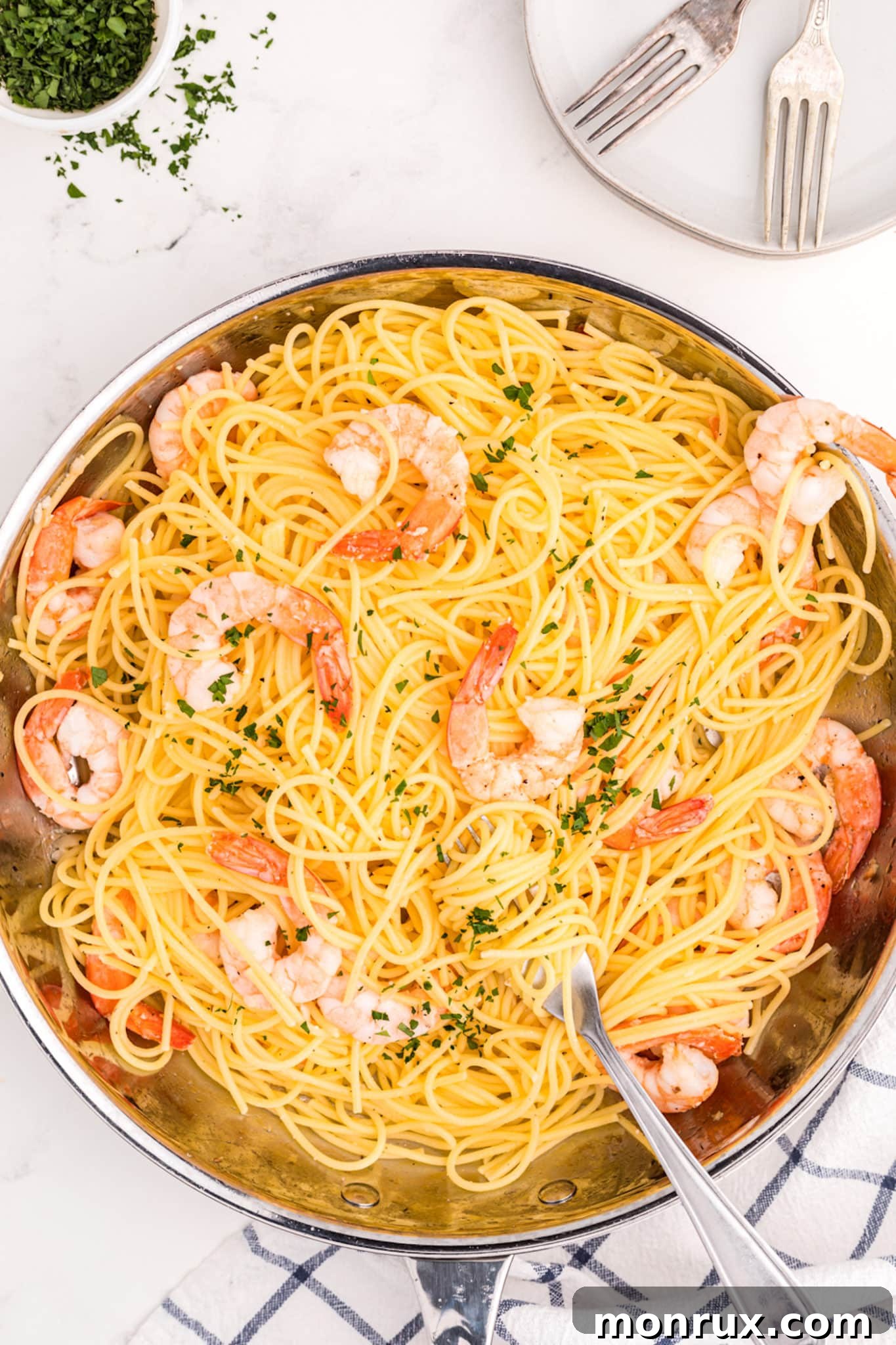 A large skillet brimming with gluten-free spaghetti and perfectly cooked, plump shrimp, all tossed in a glossy, vibrant lemon-garlic sauce.