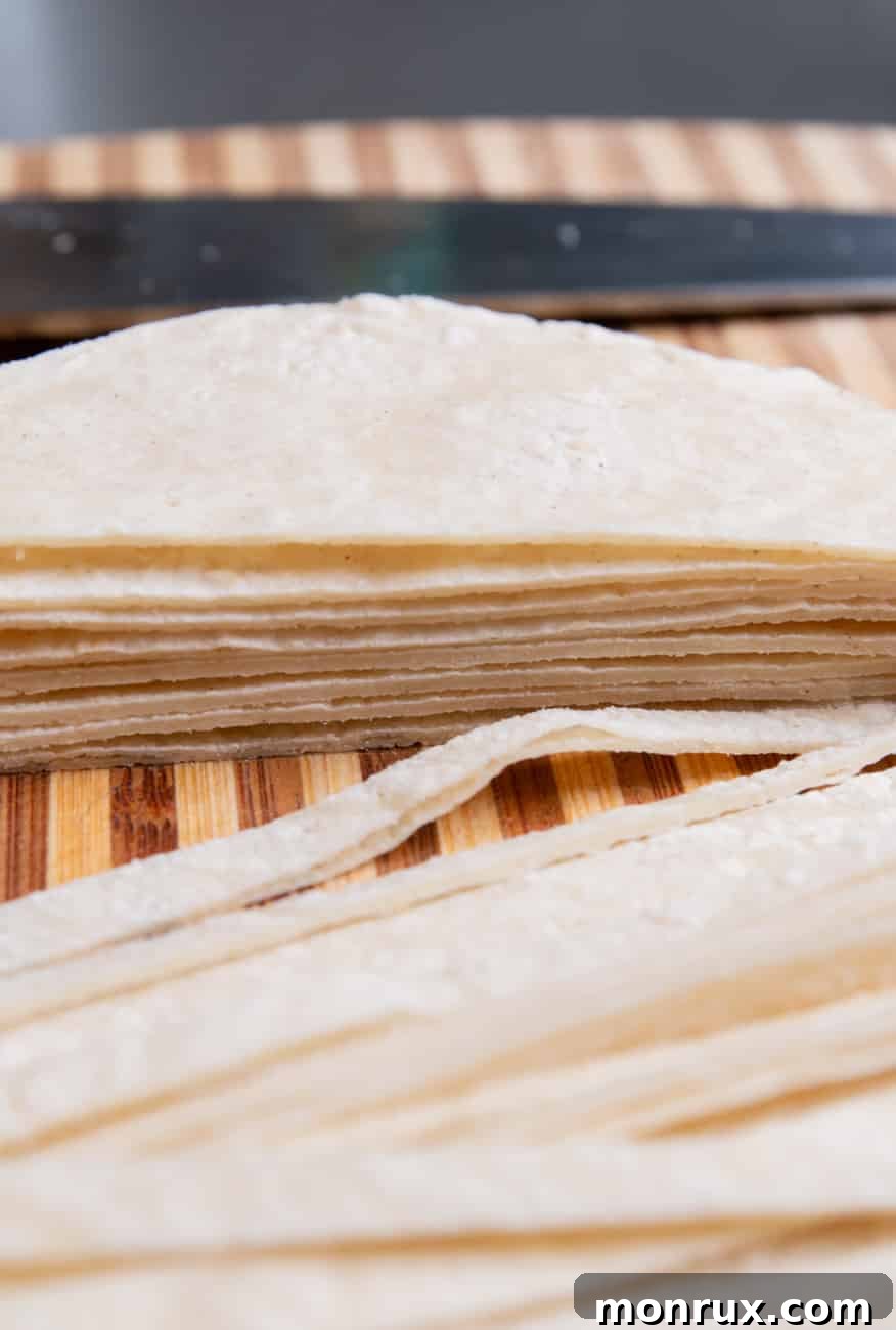 Stacked corn tortillas, expertly sliced into thin strips, ready to be baked into crispy toppings for tortilla soup.