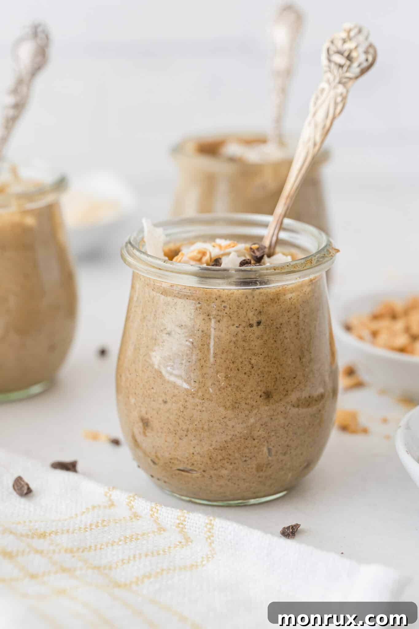 Small jars of creamy peanut butter chia pudding topped with melted chocolate and shredded coconut, ready to be served.