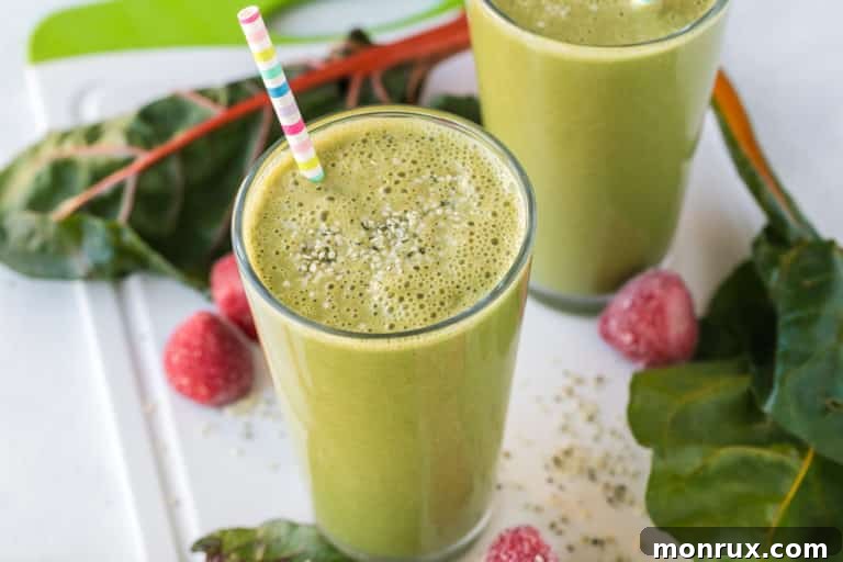 A glass of creamy Swiss chard smoothie with a straw, ready to be enjoyed.