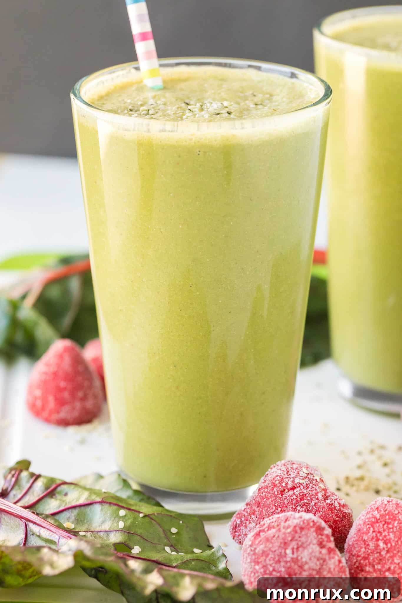 A vibrant green smoothie in a glass with a striped straw, ready to be enjoyed.