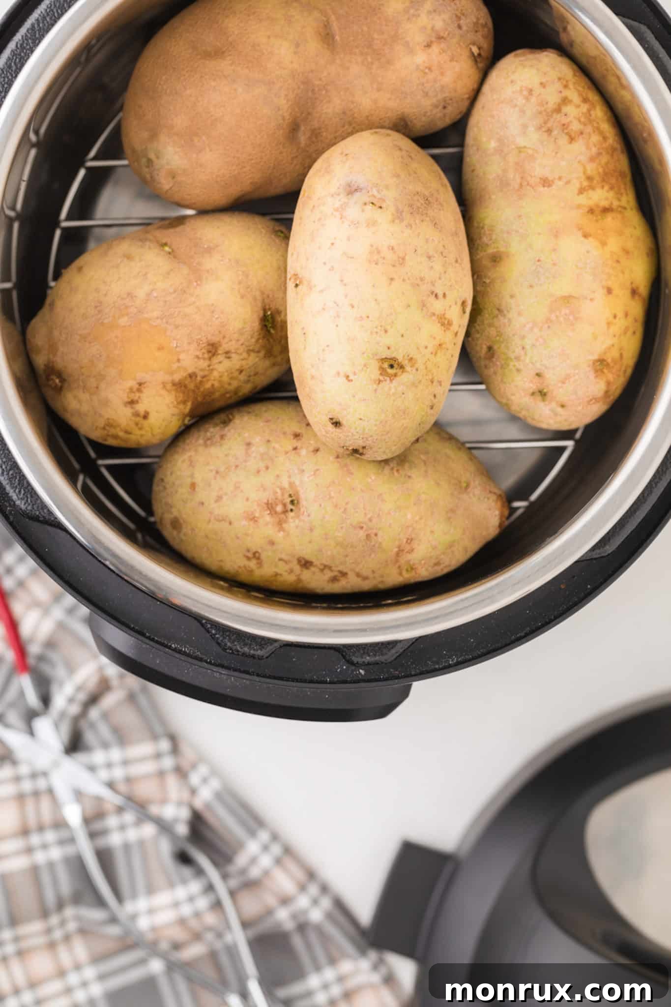 Cooked potatoes resting on a trivet inside an Instant Pot, steam gently rising.