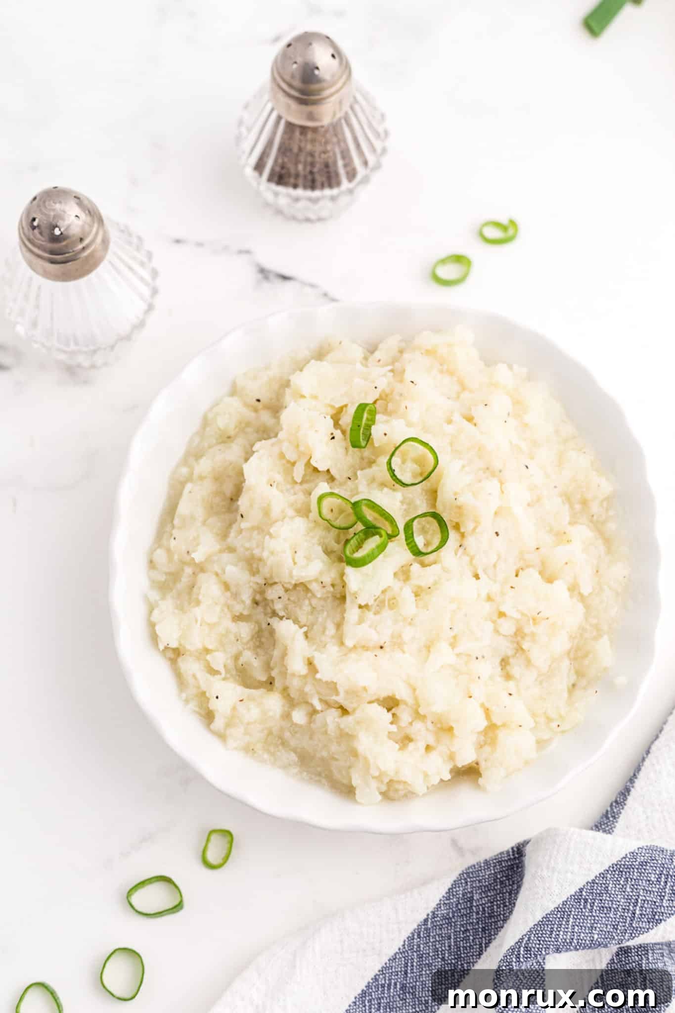 A serving of creamy cauliflower mash in a white bowl, seasoned with salt and pepper, ready for a healthy meal.