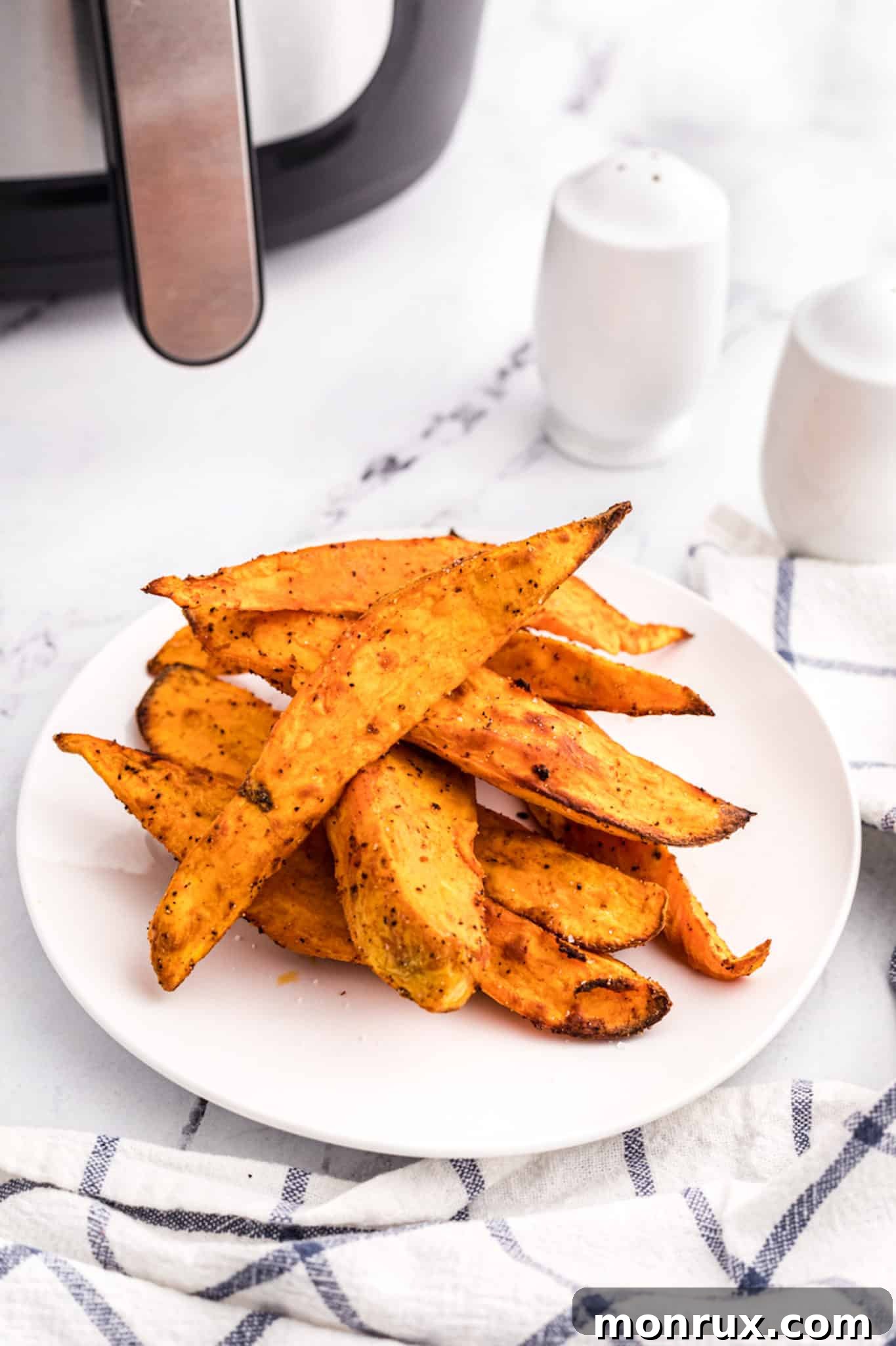 Air fried sweet potato wedges on a white plate, showcasing their crispy texture.