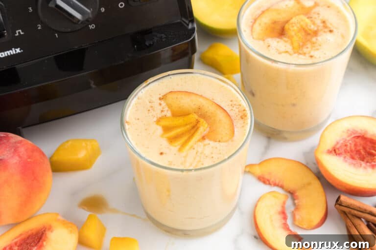 Mango Peach Smoothie in a clear glass on a wooden table, ready to be enjoyed.