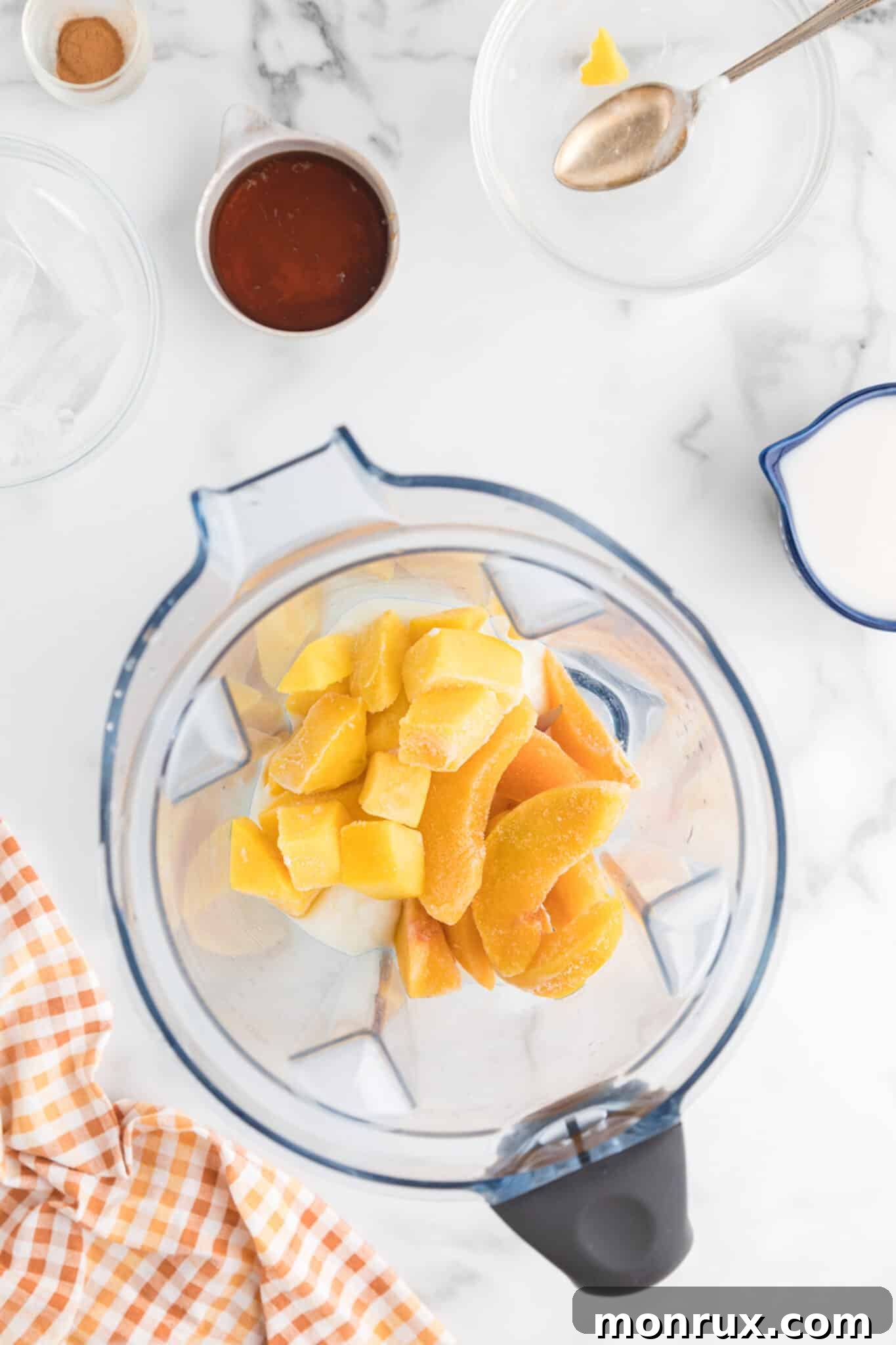 All the measured ingredients for the mango peach smoothie are carefully placed inside a high-speed blender, ready to be transformed.